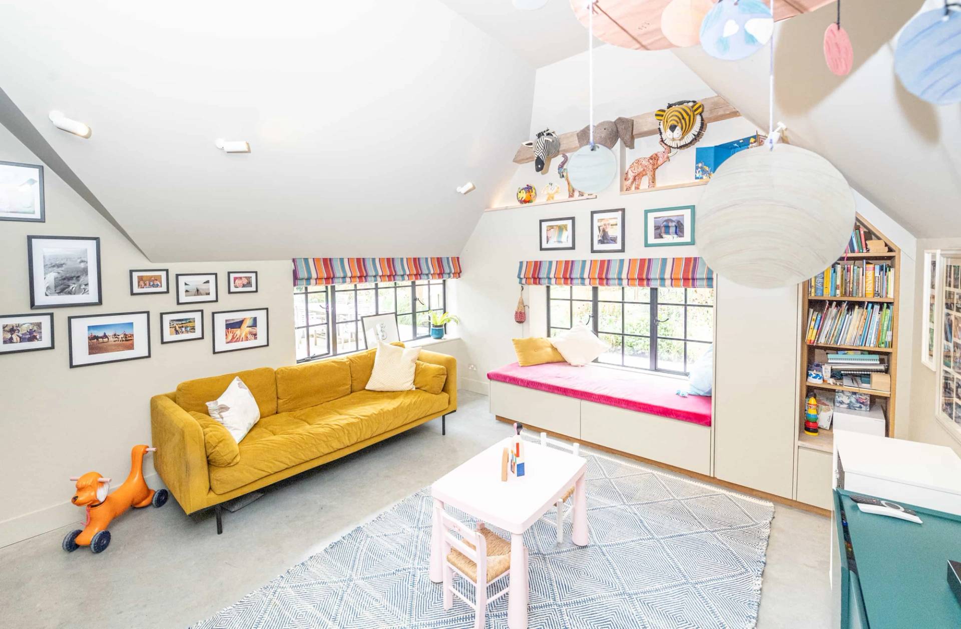 Playful kids playroom or nursery with yellow velvet sofa, pink window seat cushion, and light wood floors, Love Locations GU28.