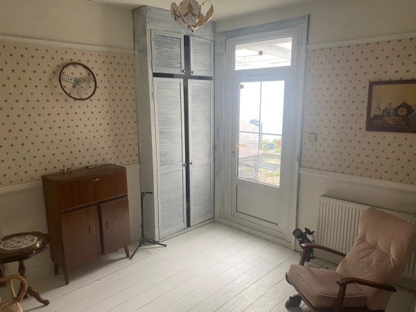 Simple, uncluttered room featuring a distressed wardrobe cabinet and a glazed balcony door casting soft light, ideal for documentary video backdrops, Love Locations SE25.