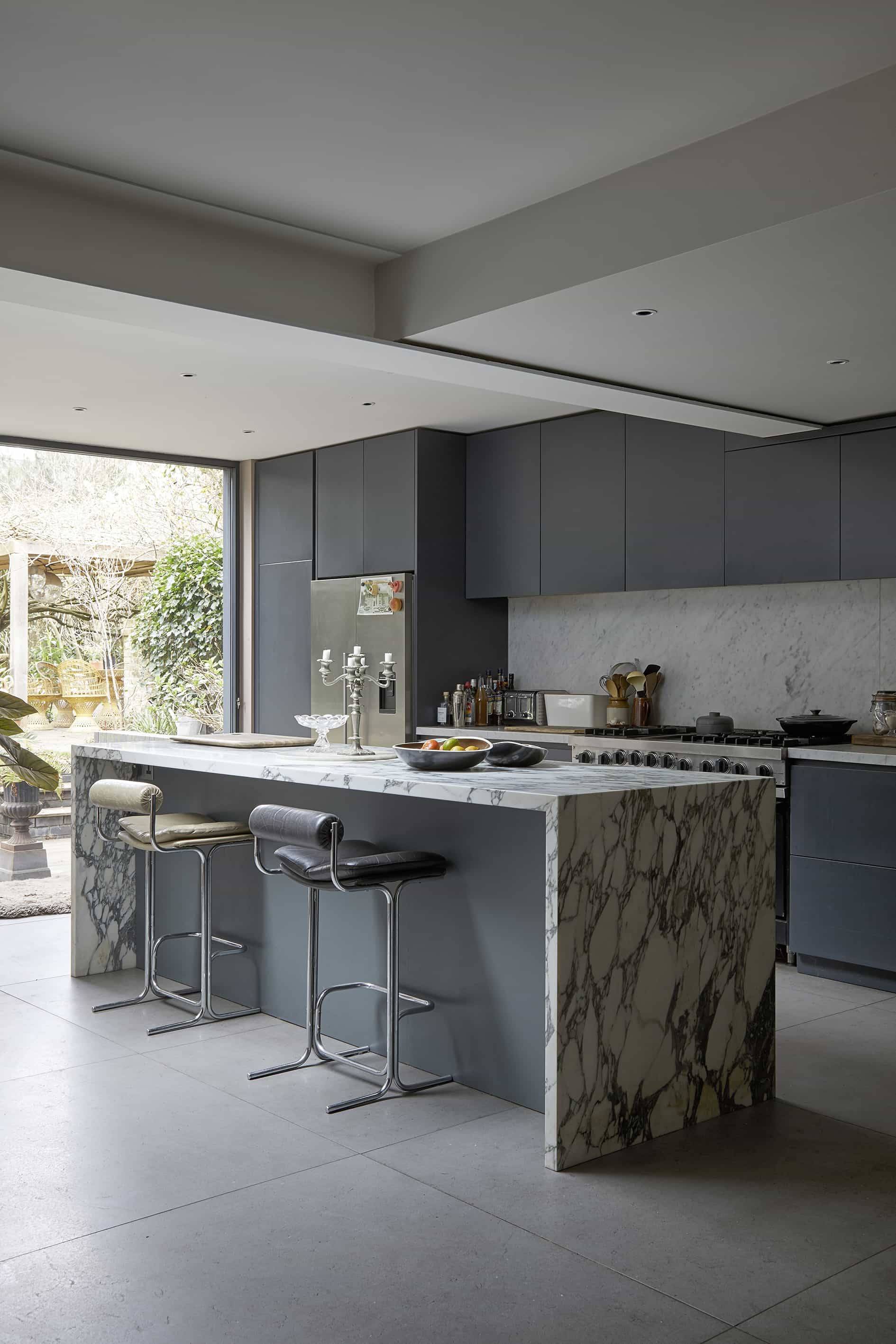 Modern kitchen island with dark veined marble waterfall counter and chrome bar stools, ideal for food ads, Love Locations N16.