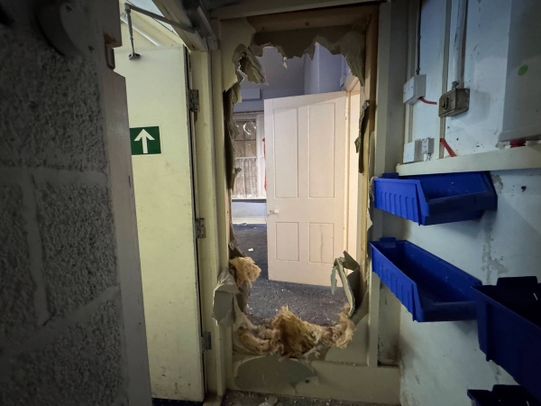 Heavily damaged partition wall with a smashed hole revealing a classic white panel door, authentic ruin set by Love Locations.