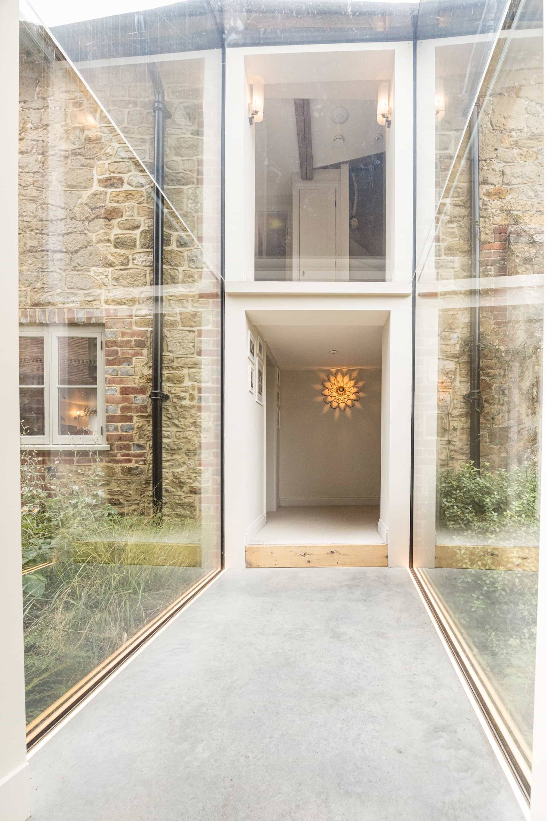 Glass link corridor view looking onto an internal gravel courtyard with potted plants, Love Locations GU28.