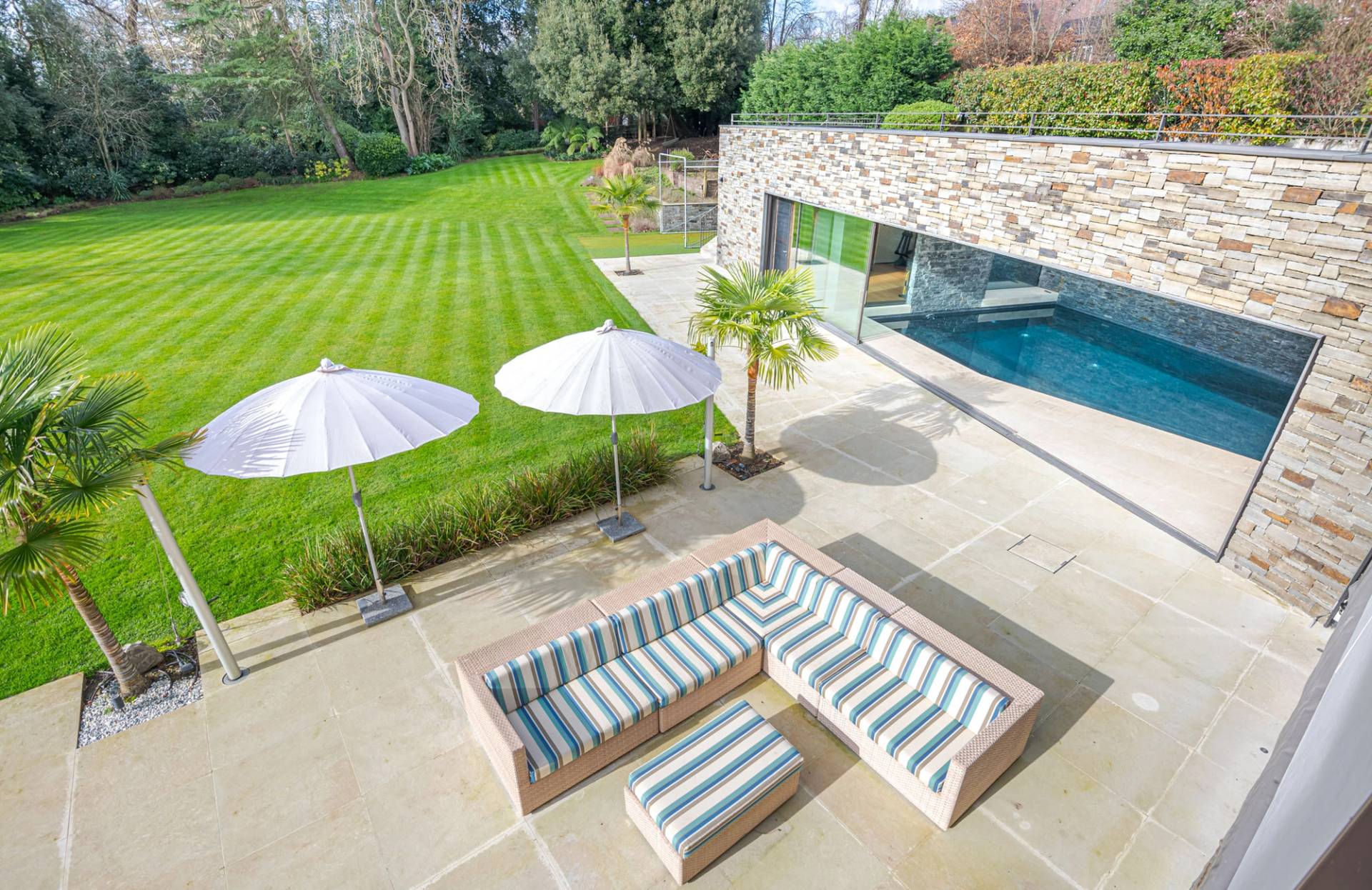 High-angle view of a luxury outdoor patio with striped seating and garden grounds in Kingston upon Thames, Love Locations KT2.
