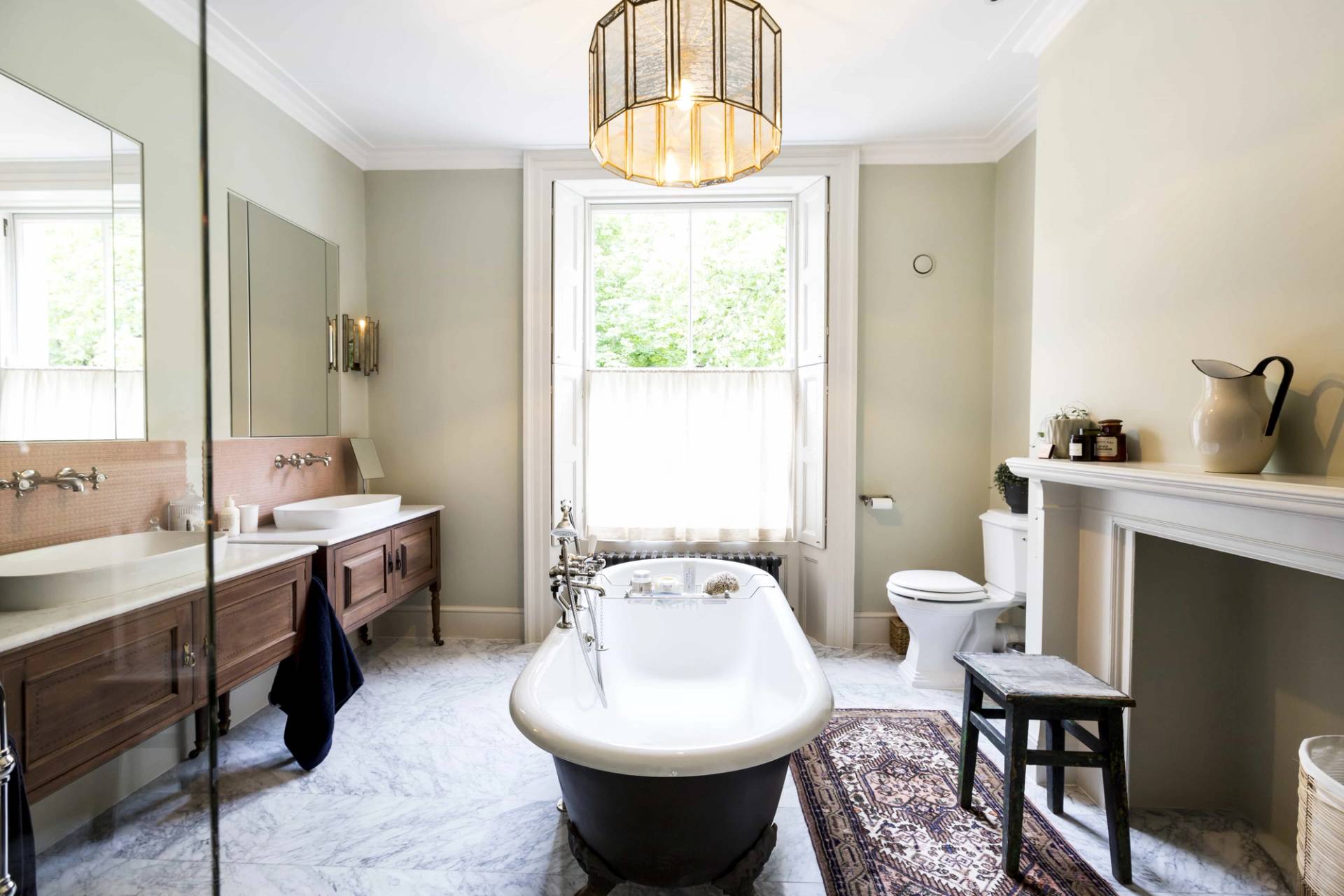 Freestanding clawfoot tub and marble vanity unit in a light sage green bathroom in SE5 via Love Locations.