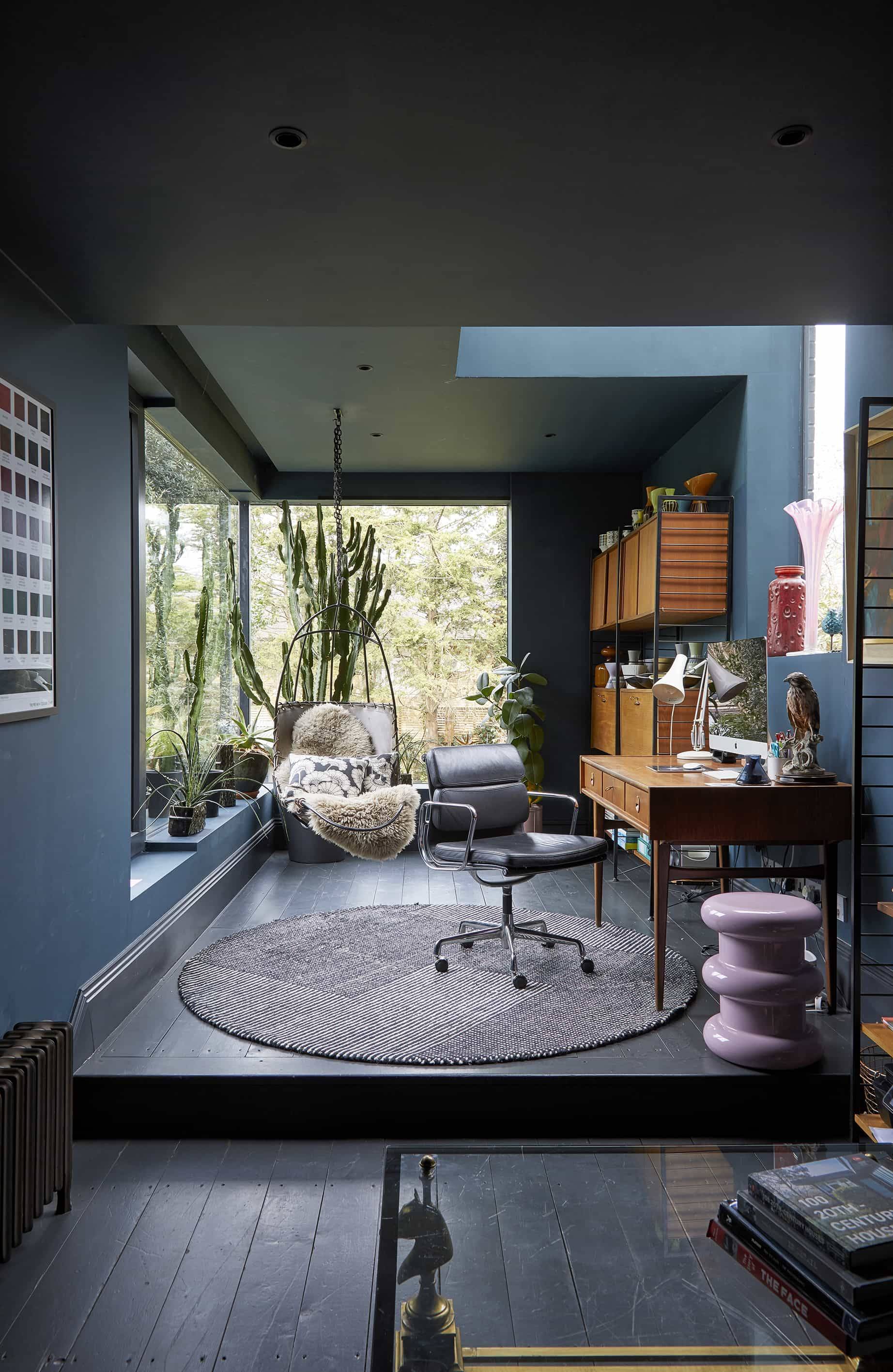 Dark blue study nook featuring a dark writing desk, circular grey rug, office chair, and full-height window, Love Locations N16.