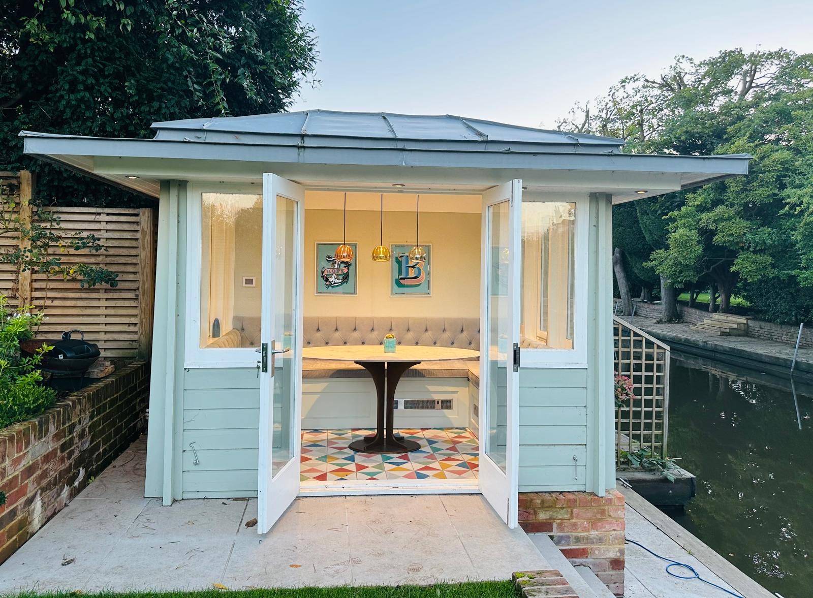 Clad garden summerhouse studio with open French doors showing an interior dining booth setup, Love Locations TW11.