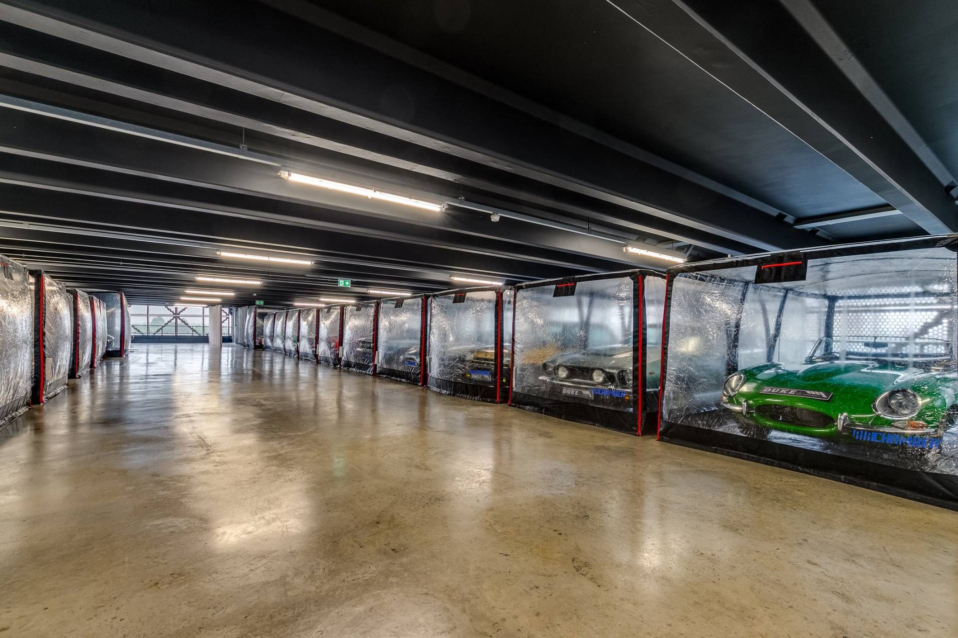 Polished concrete hall with rows of encapsulated luxury cars in a Brentford TW8 shoot space via Love Locations.