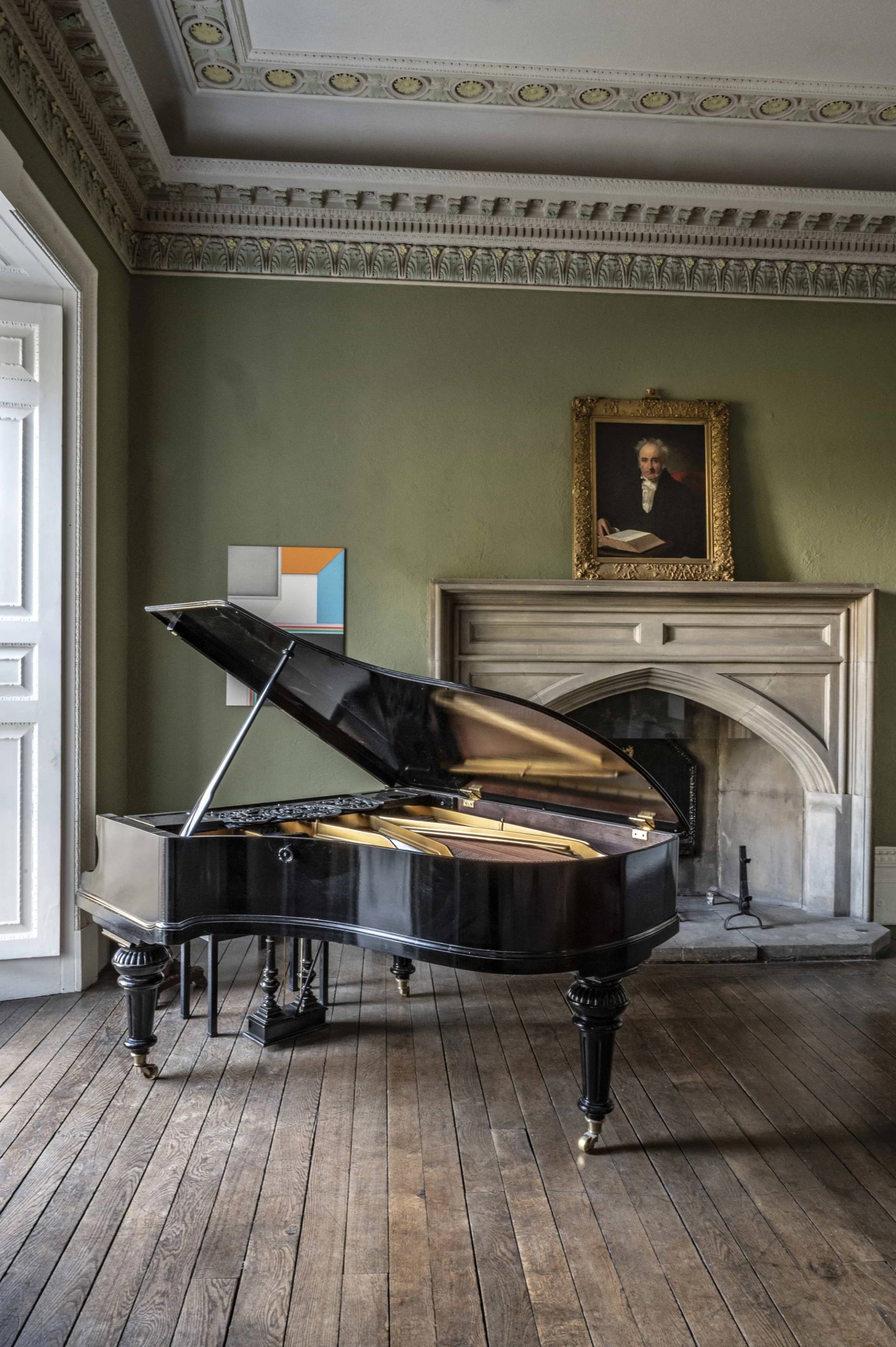Black grand piano positioned in an ornate fireplace alcove within a sage green country house room, ideal for music video filming, Love Locations.