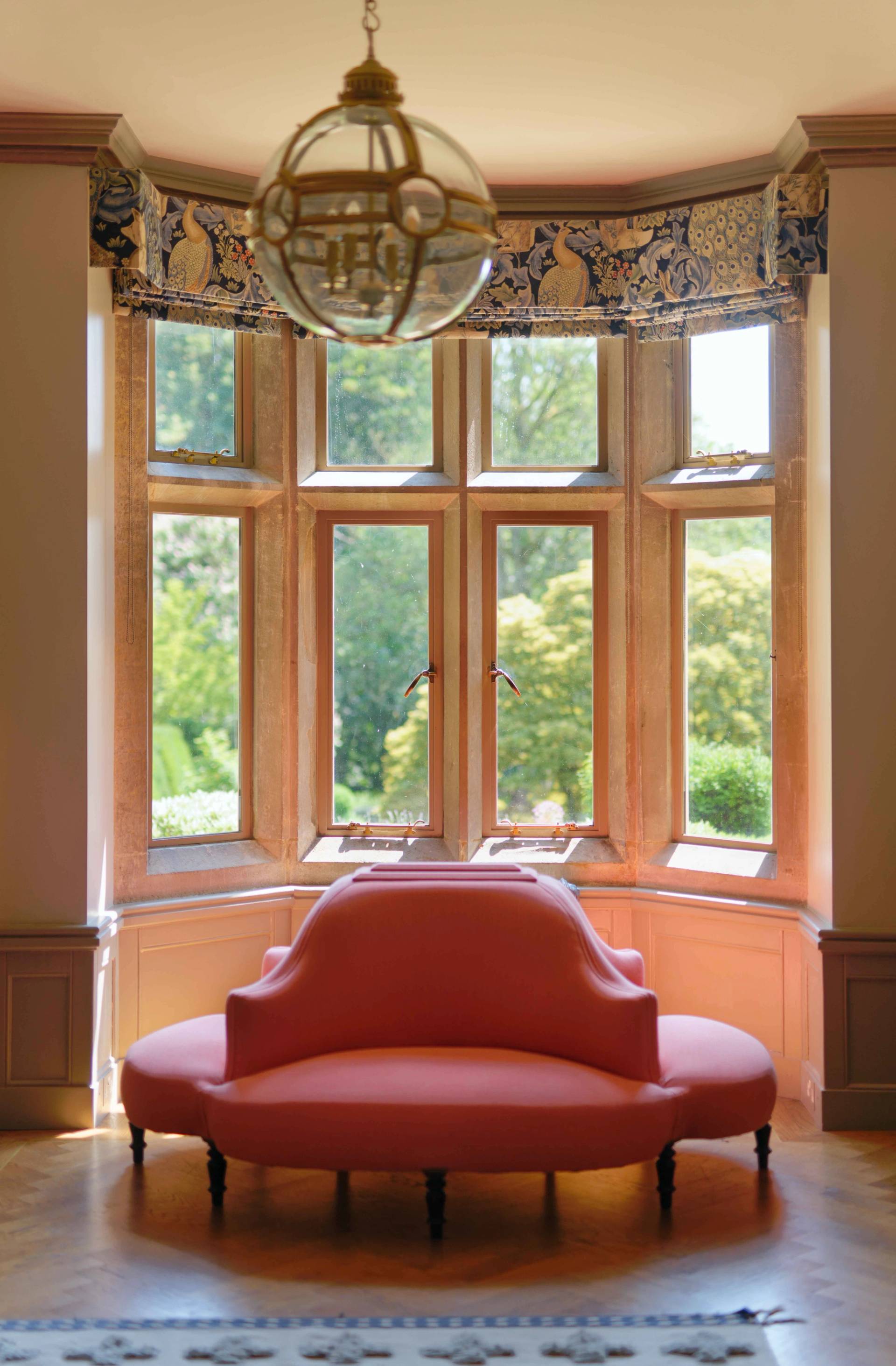 Stone mullion bay window setting with a terracotta curved bench seat cast in natural light, Love Locations OX7.