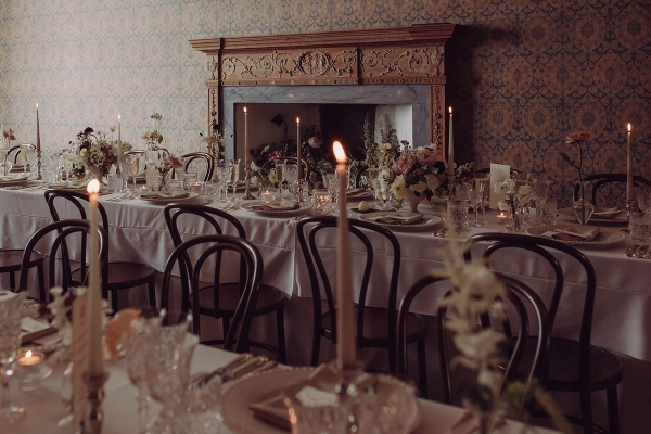 Event dining setup in front of a stone fireplace with glowing candles and rustic chairs, Love Locations KY15.