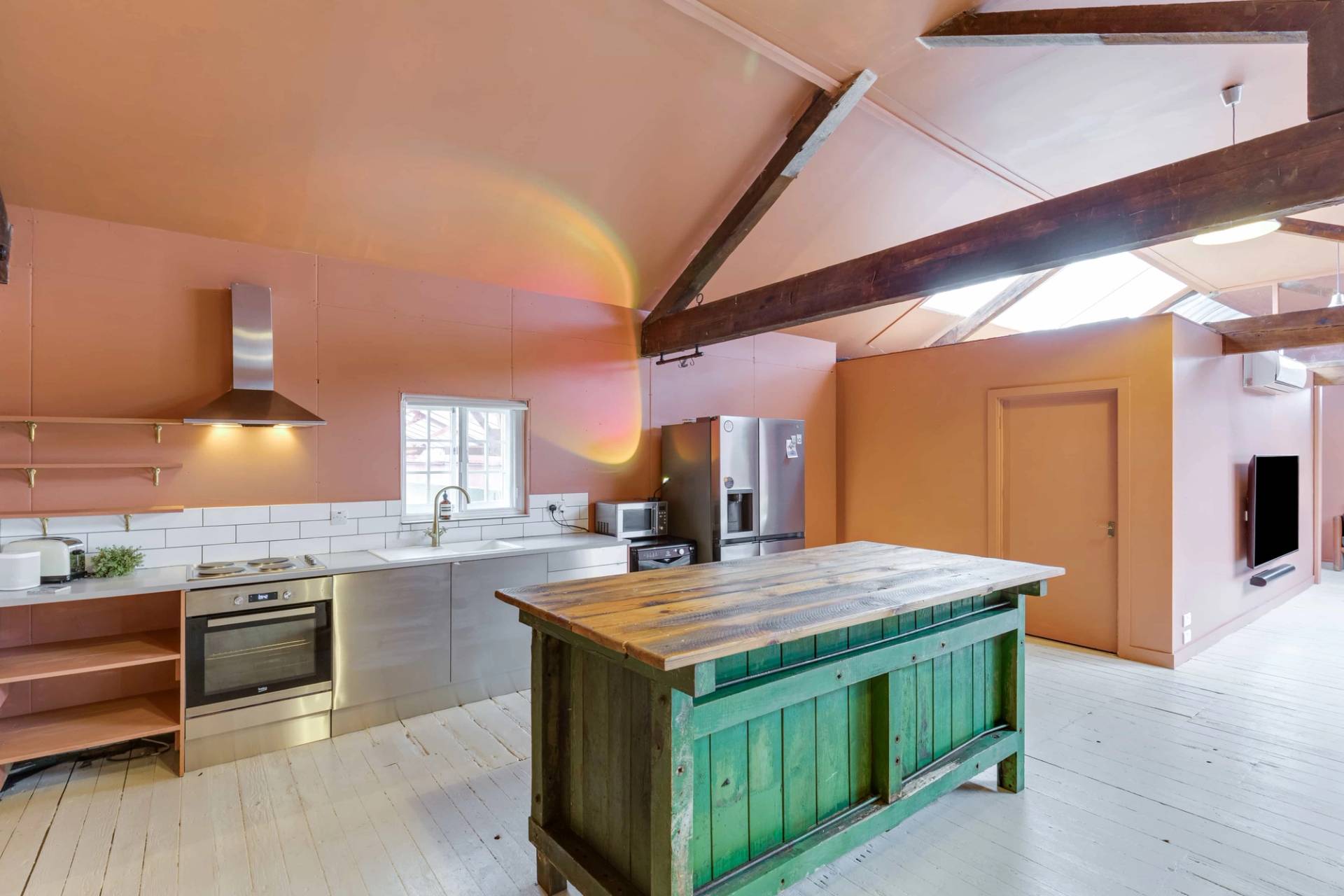 Modern-industrial kitchen film location with sleek steel appliances and warm pink plaster walls, Love Locations.