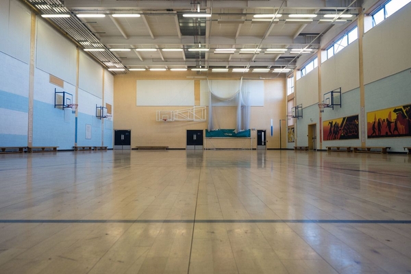 Love Locations indoor sports hall film location BS7: Sprawling school gymnasium floor with basketball hoops and high windows, optimized for high-energy sports commercials and athletic training videos.