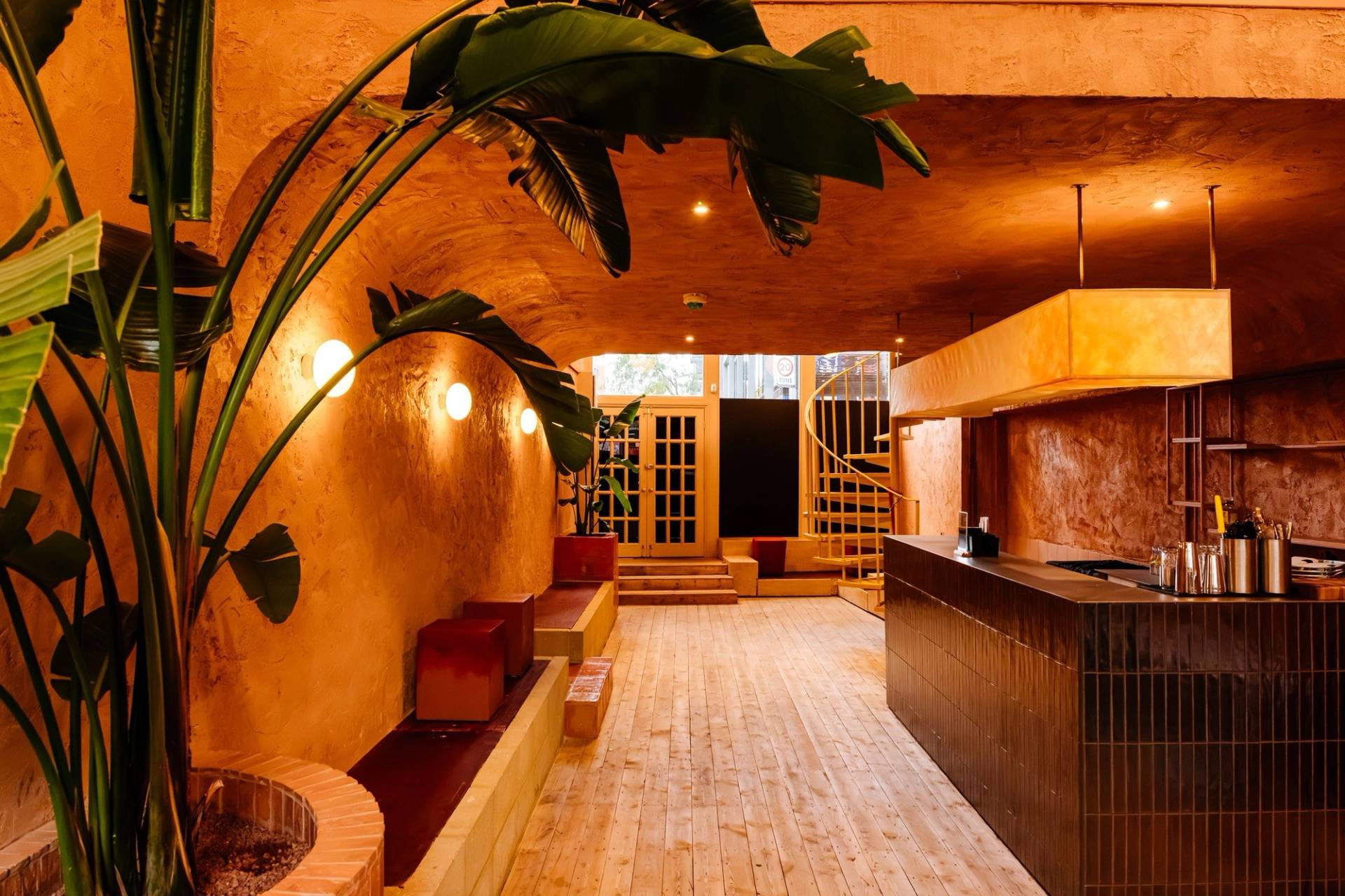 Stylish bar area and cocktail lounge featuring curved plaster walls, warm lighting, and natural wood accents through Love Locations.