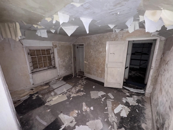 Run-down bedroom featuring heavily damaged ceilings, debris, and classic panel doors, a premium distressed location by Love Locations.