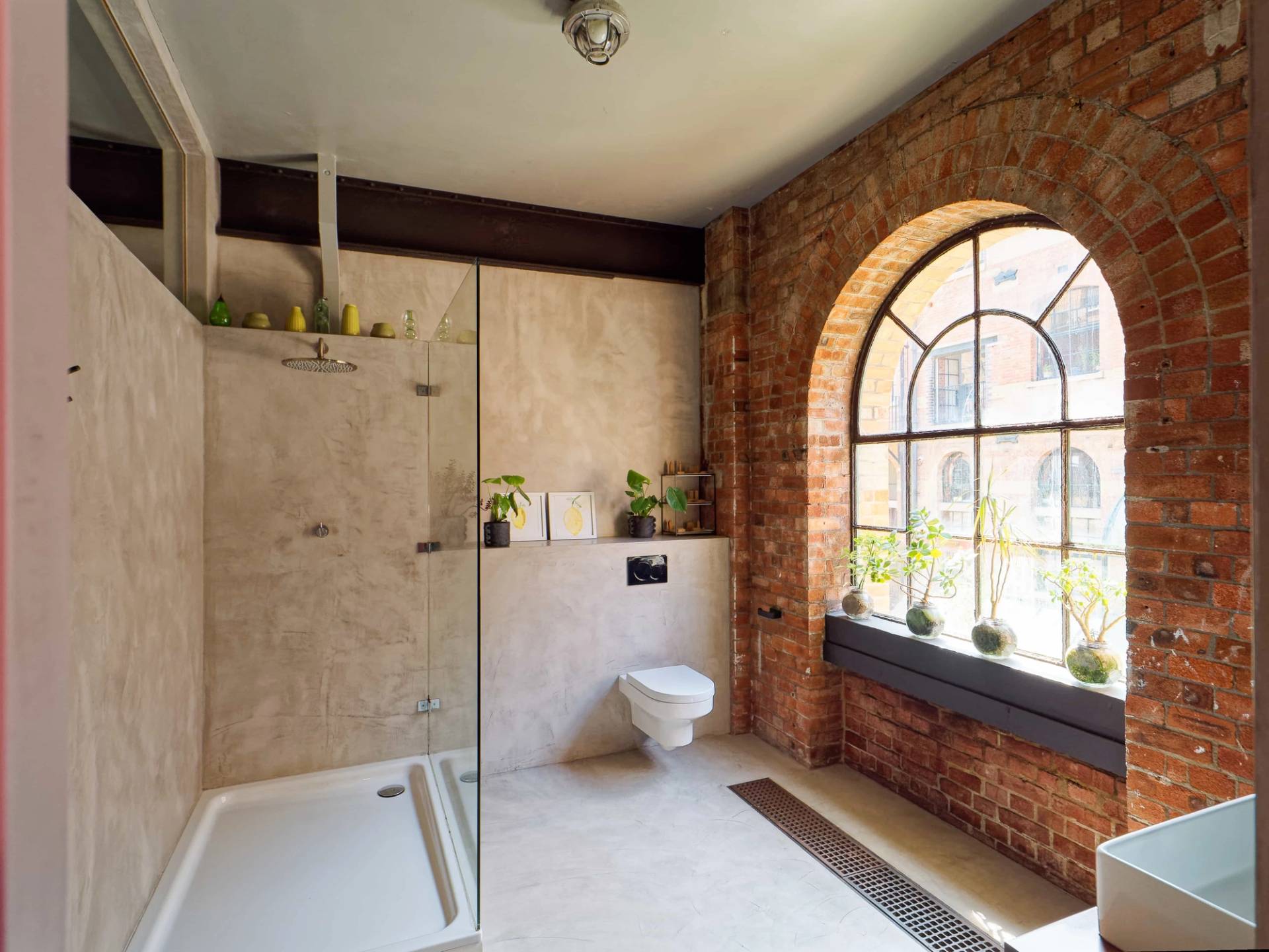 Micro-cement wet room shower space with polished concrete walls and large arched window light in E14, Love Locations.