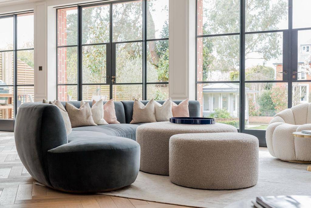 Contemporary lounge seating corner featuring a curved grey sectional sofa and Crittall glazing, Love Locations TW11.