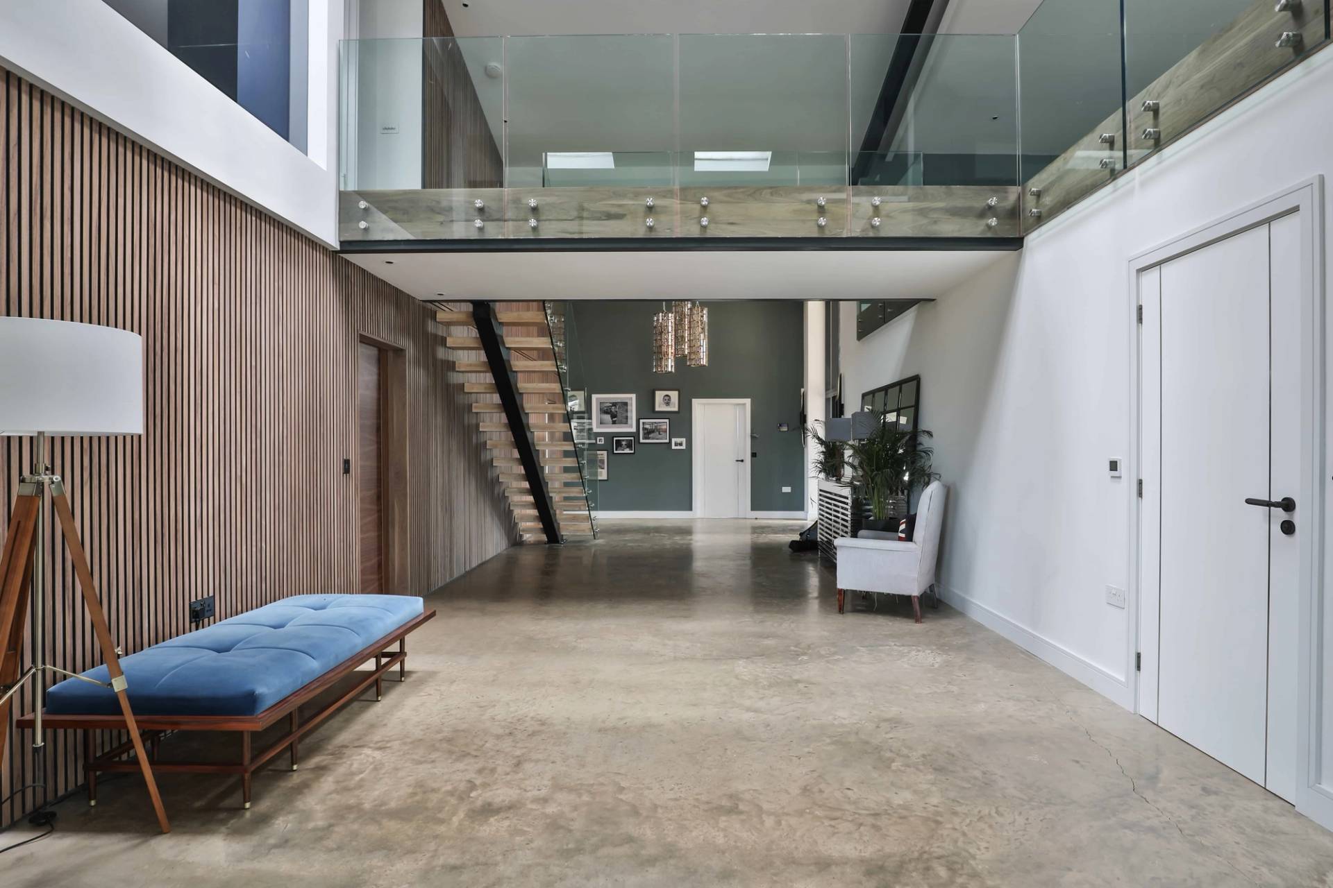 Double-height entrance hall featuring a floating wooden staircase, glass balustrade, and polished concrete flooring, Love Locations CV23.