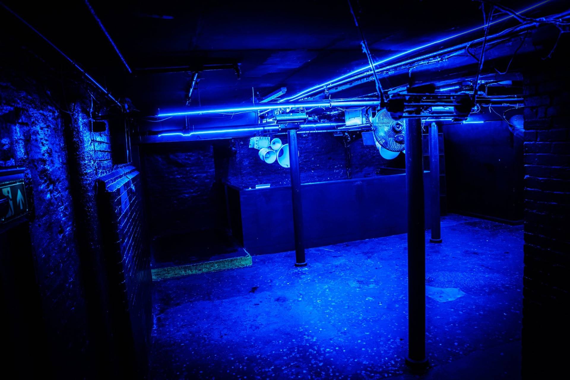 Angled shot of a blue-lit club floor and DJ desk in an industrial Manchester M3 event venue by Love Locations.