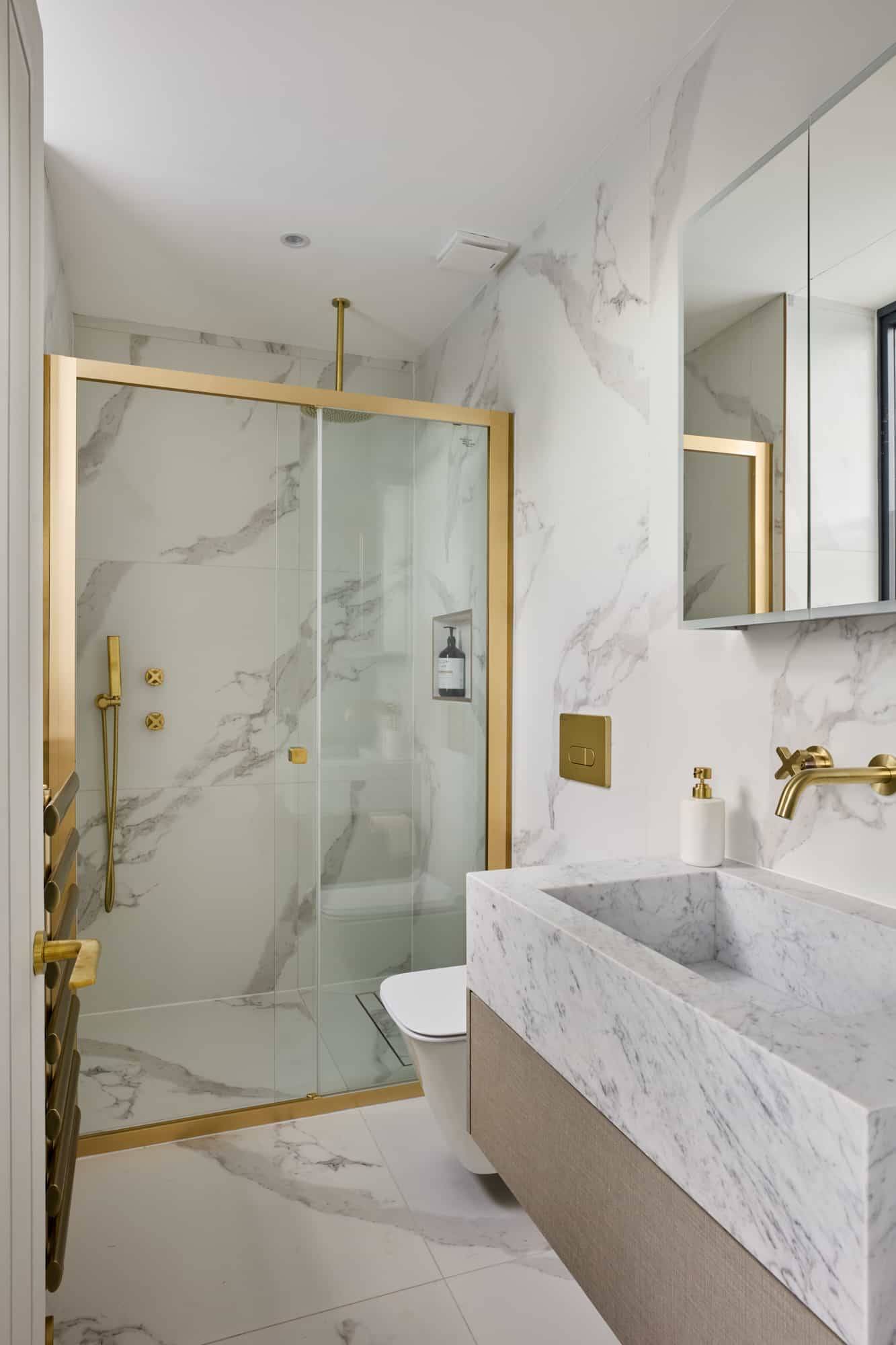 Luxury master bathroom featuring marble tile walls, gold brass tapware, glass shower enclosure, and custom vanity, perfect for skincare commercials via Love Locations KT22.
