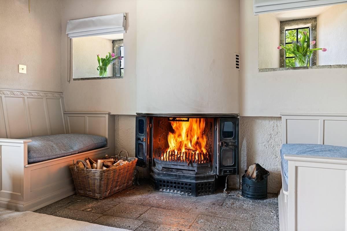 Inglenook brick fireplace with a roaring log fire and stone hearth in a historic country home, Love Locations RH13.