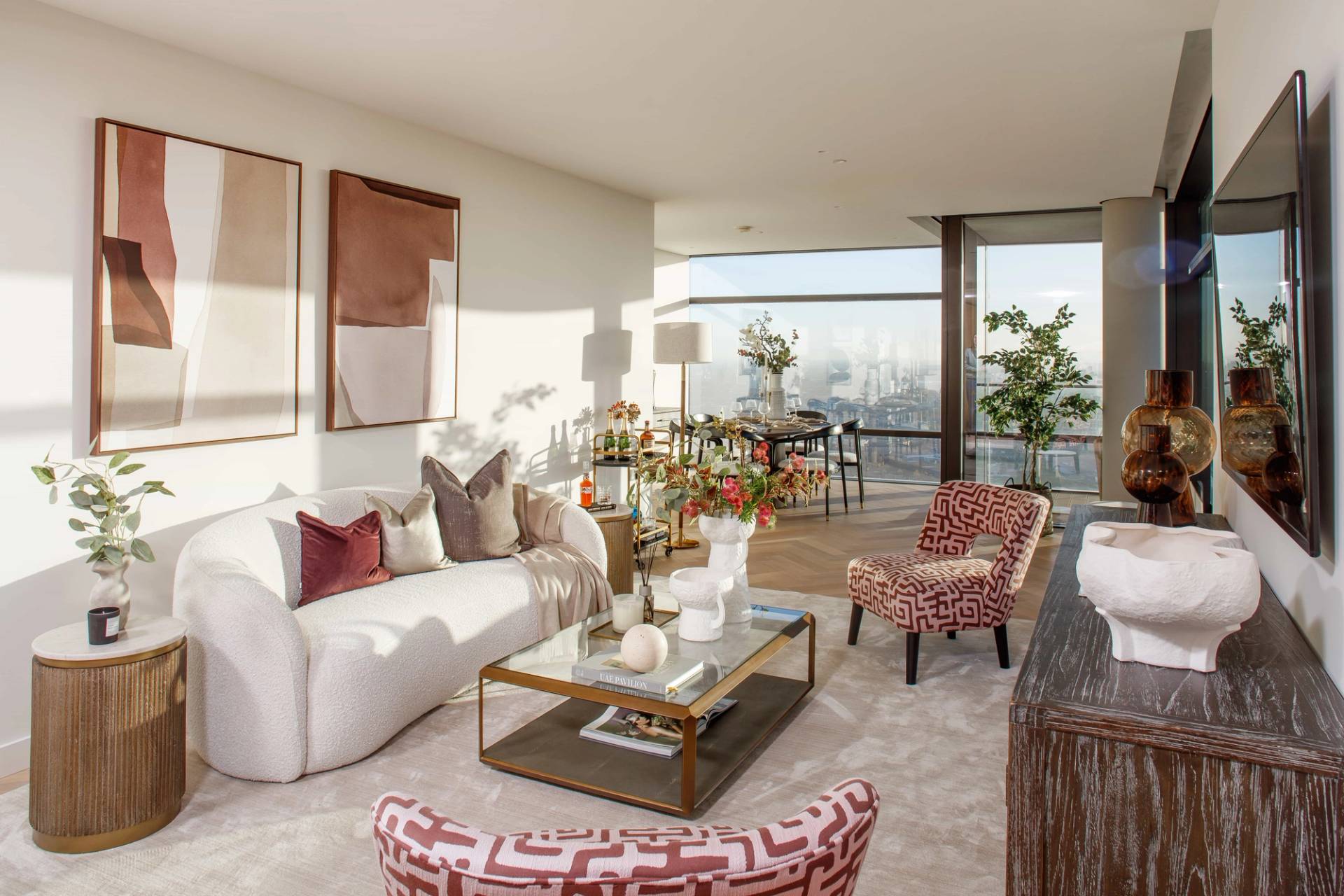 Luxury penthouse living room shoot location in East London, EC2A near Liverpool Street Station featuring curved cream sofa, geometric armchairs, and floor-to-ceiling London skyline views, ideal for high-end lifestyle commercials via Love Locations.