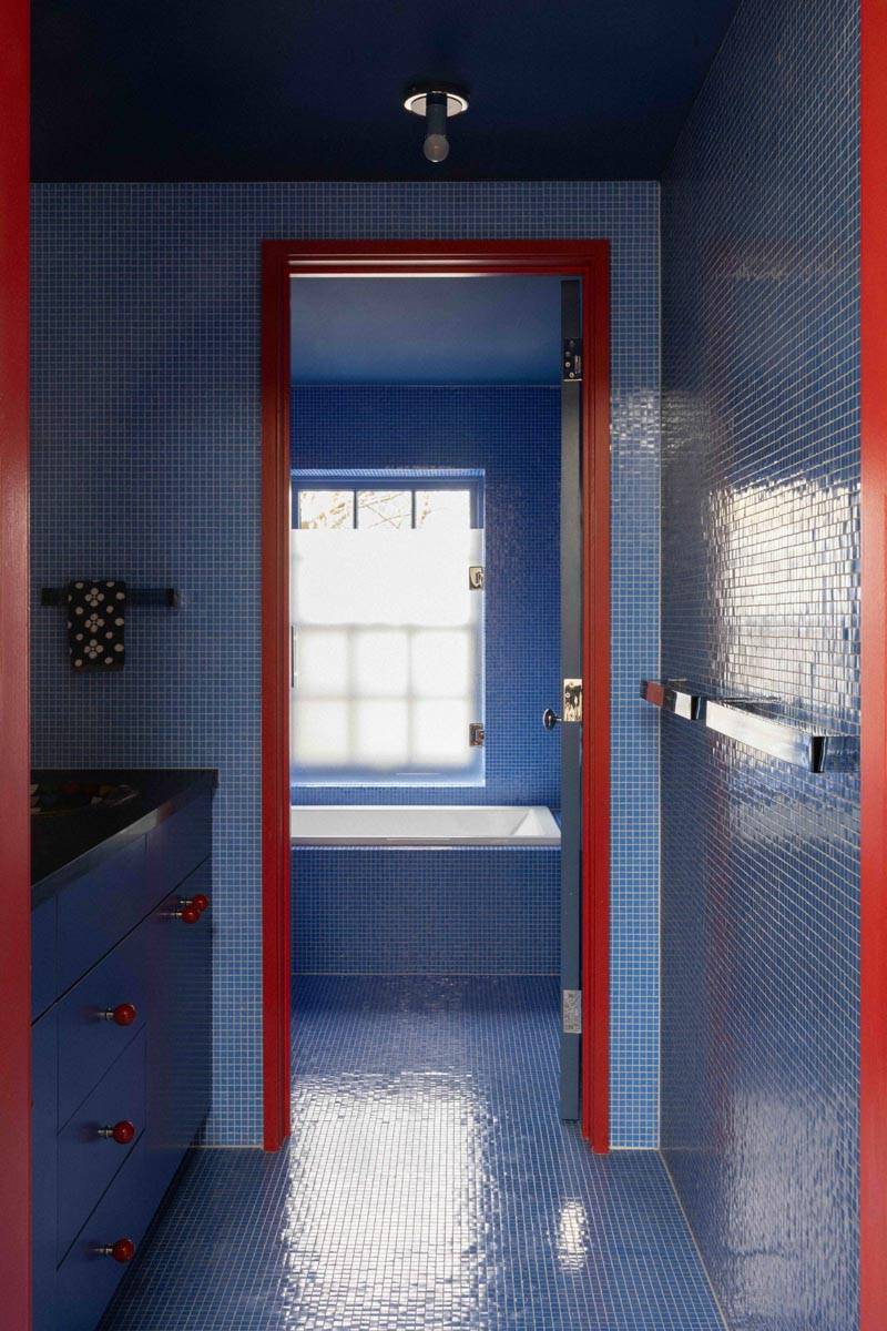Doorway view into a blue mosaic tiled bathroom filming location in a Brooklyn NY 11217 townhouse by Love Locations, highlighted by red door frames.