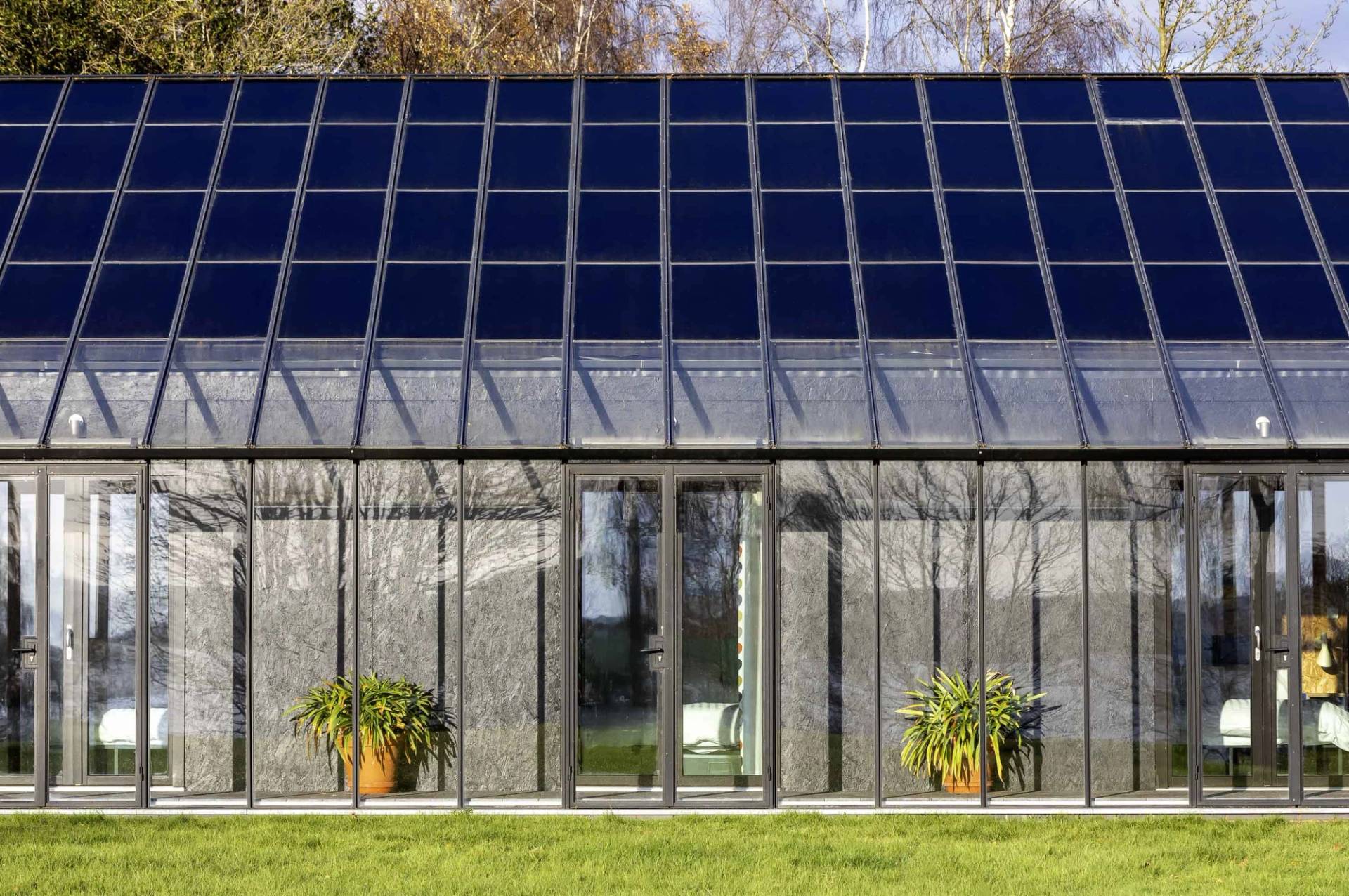 Glass greenhouse facade with solar-panelled roof structure and glass double entrance doors, Love Locations IP17.