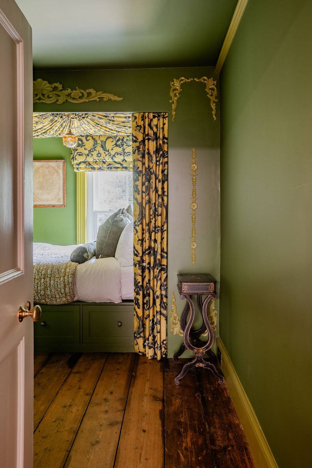 Enclosed view into a sage green bedroom location featuring bold black-and-gold patterned curtains, a premium production asset from Love Locations.