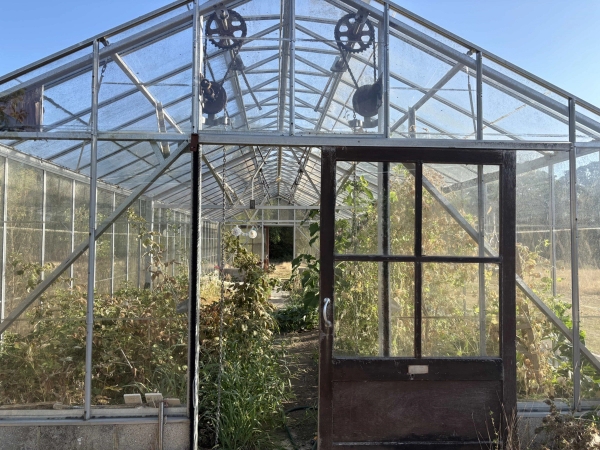 Industrial greenhouse frame interior view with pulley gear mechanisms and open sliding doors, Love Locations BN8.
