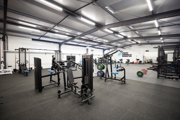 Wide angle of a fully equipped commercial gym floor showing varied strength and conditioning machines in Winchester, SO23, Love Locations.