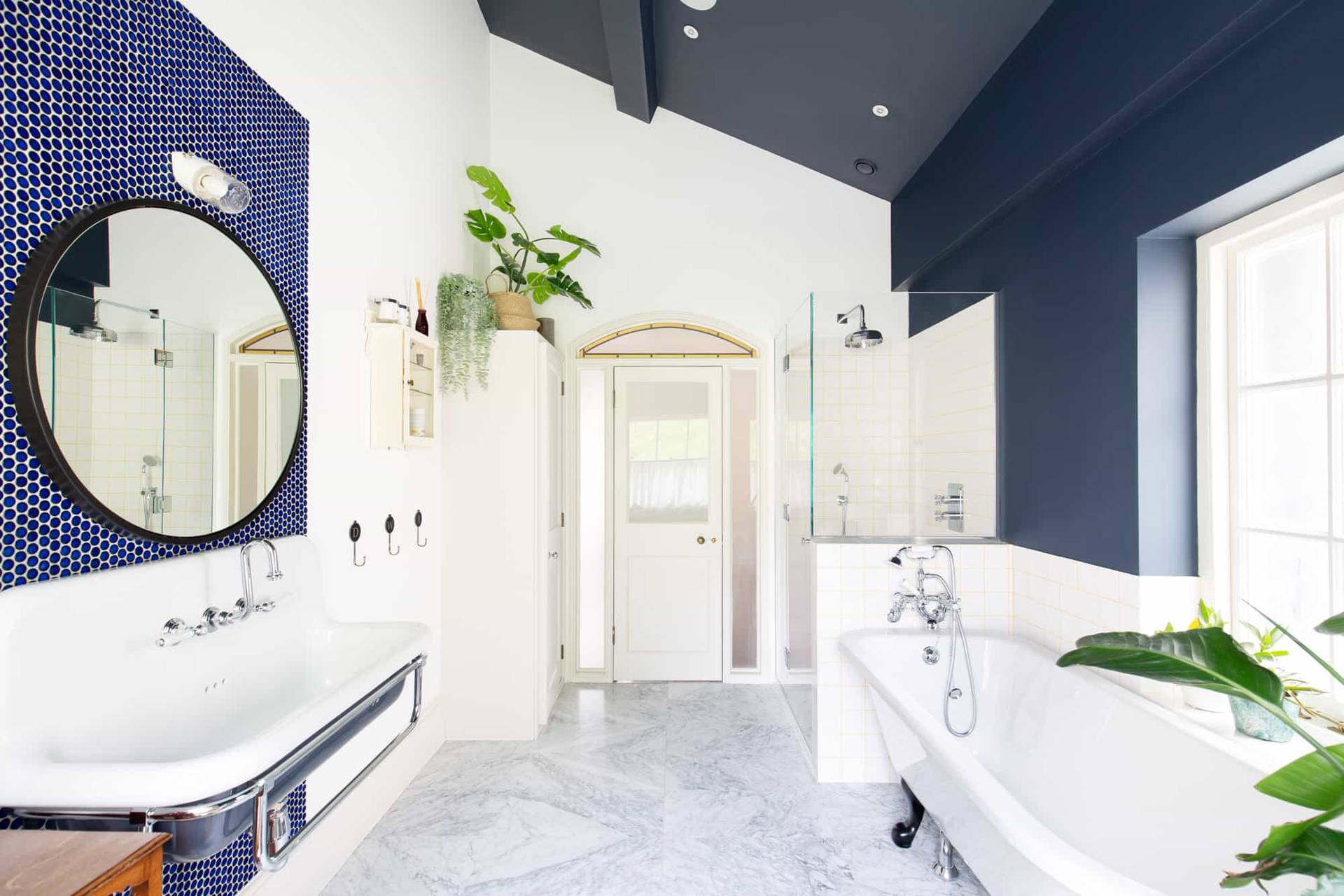 Attic bathroom shoot location in Camberwell, SE5 featuring pitched navy ceiling, freestanding white tub, and marble tiles via Love Locations.