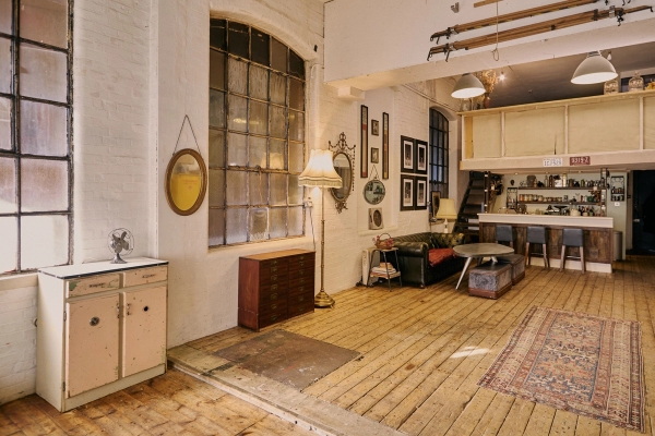 Open-plan warehouse studio interior showcasing factory window lighting, a vintage writing desk, and rustic decor details, Love Locations EN5.