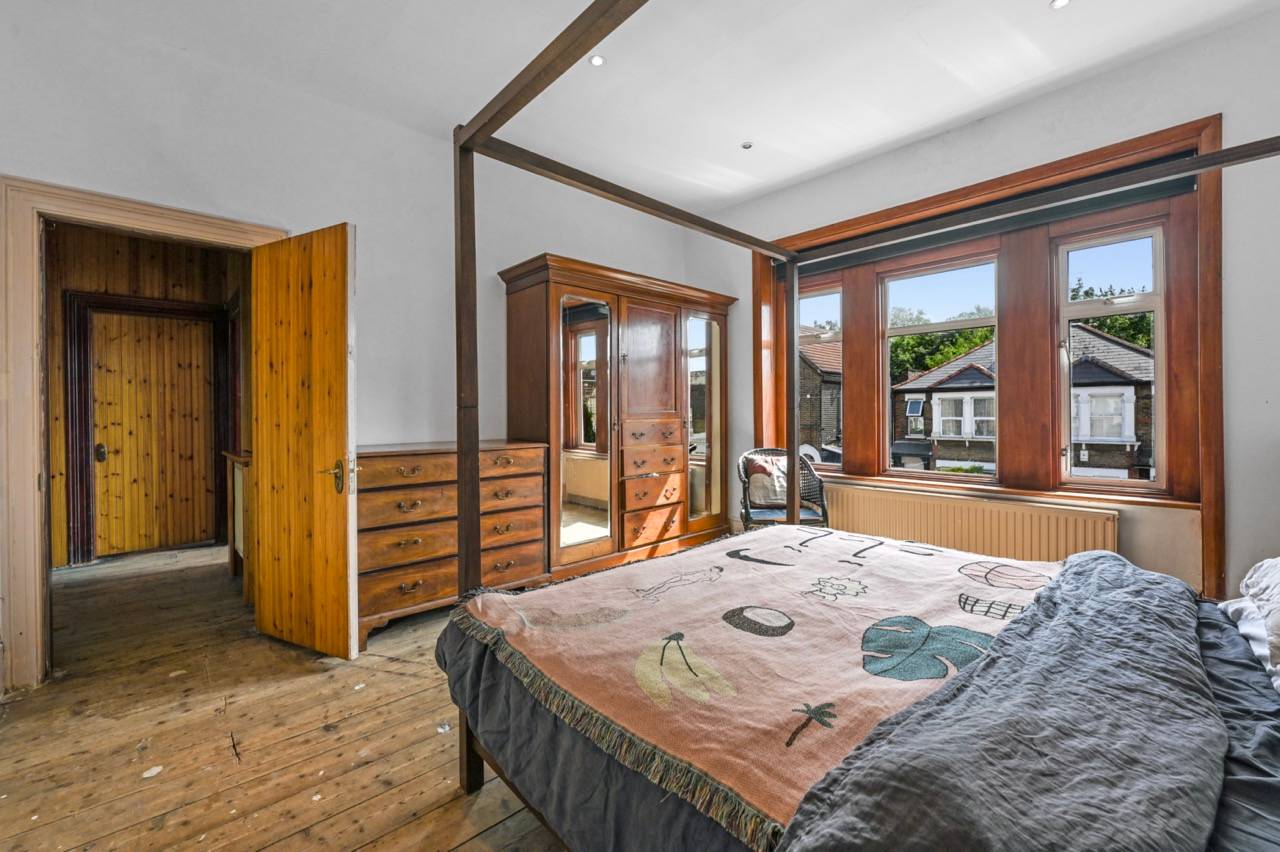 Secondary bedroom featuring exposed timber ceiling joists, wooden wardrobe, and bay windows, Love Locations.