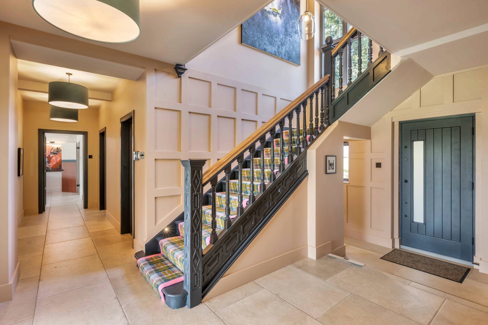 Grand entrance hallway featuring a dark wood stairwell, tartan carpet runner, and oak wall panelling in a Surrey estate, Love Locations GU27.