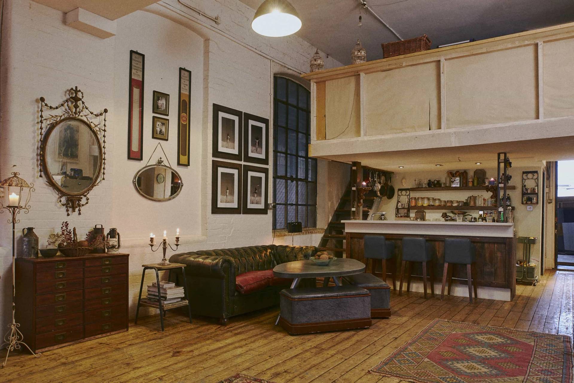 Industrial mezzanine lounge backdrop showing a green leather sofa and elevated bar counter inside an 1890s warehouse, Love Locations.