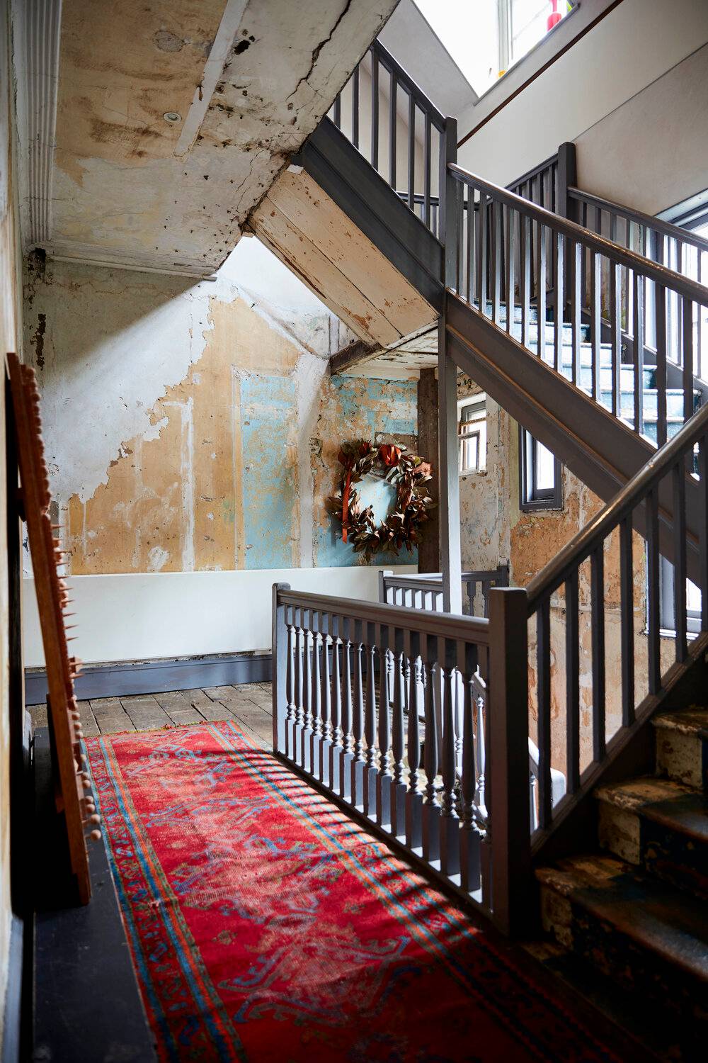 Stairwell landing view looking up a dark wooden staircase with exposed wall brickwork and skylights, Love Locations.
