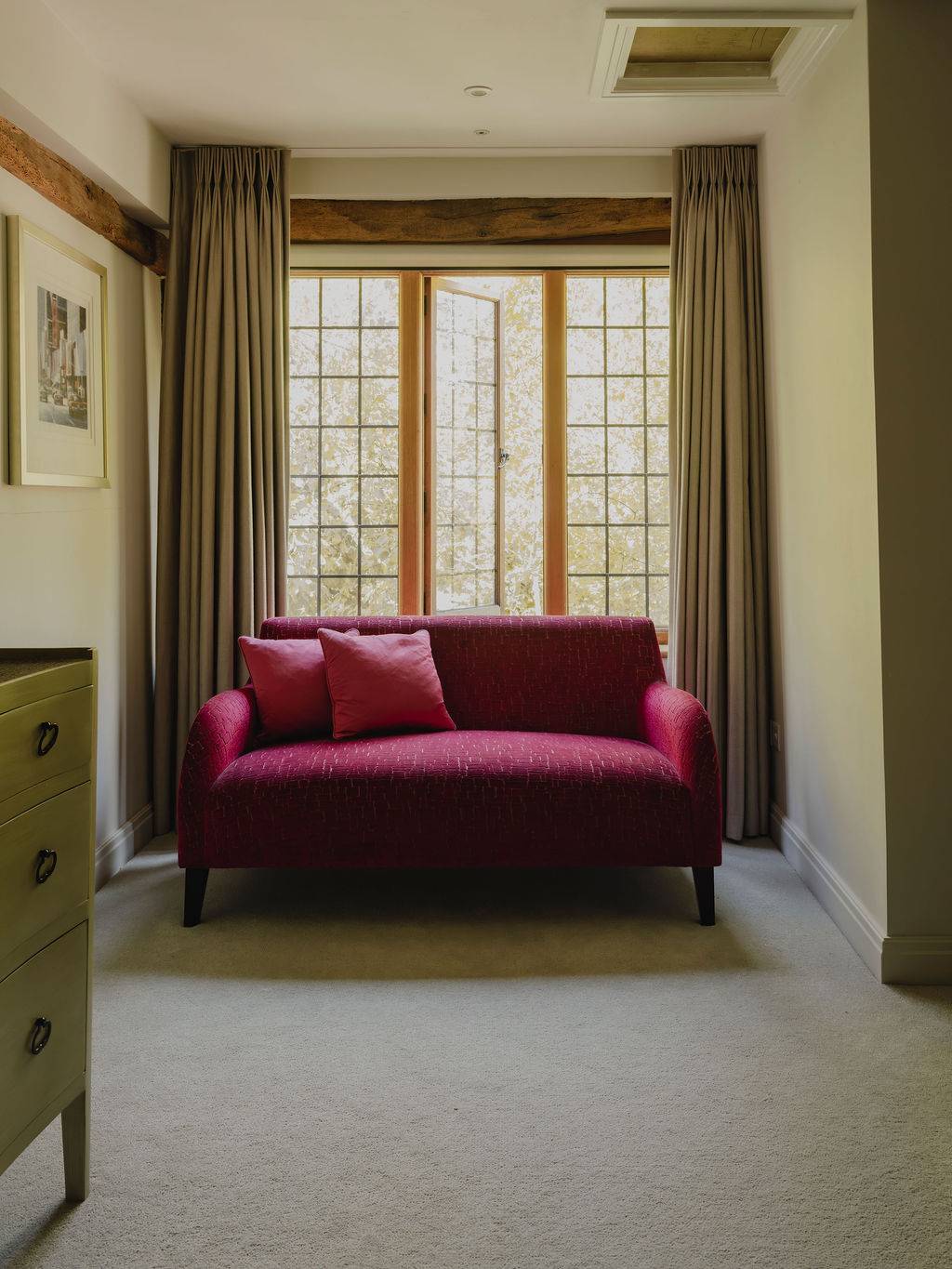 Master bedroom seating nook with a vibrant magenta armchair set beside a leaded grid window, perfect for lifestyle editorial photography, Love Locations RG9.