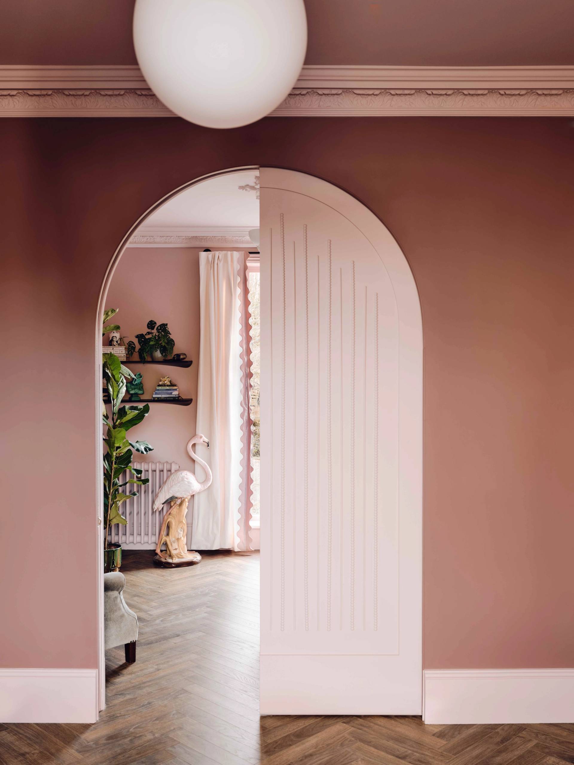 Bespoke pink panelled arched door partially opened to reveal a bright bedroom suite, Love Locations CR0.
