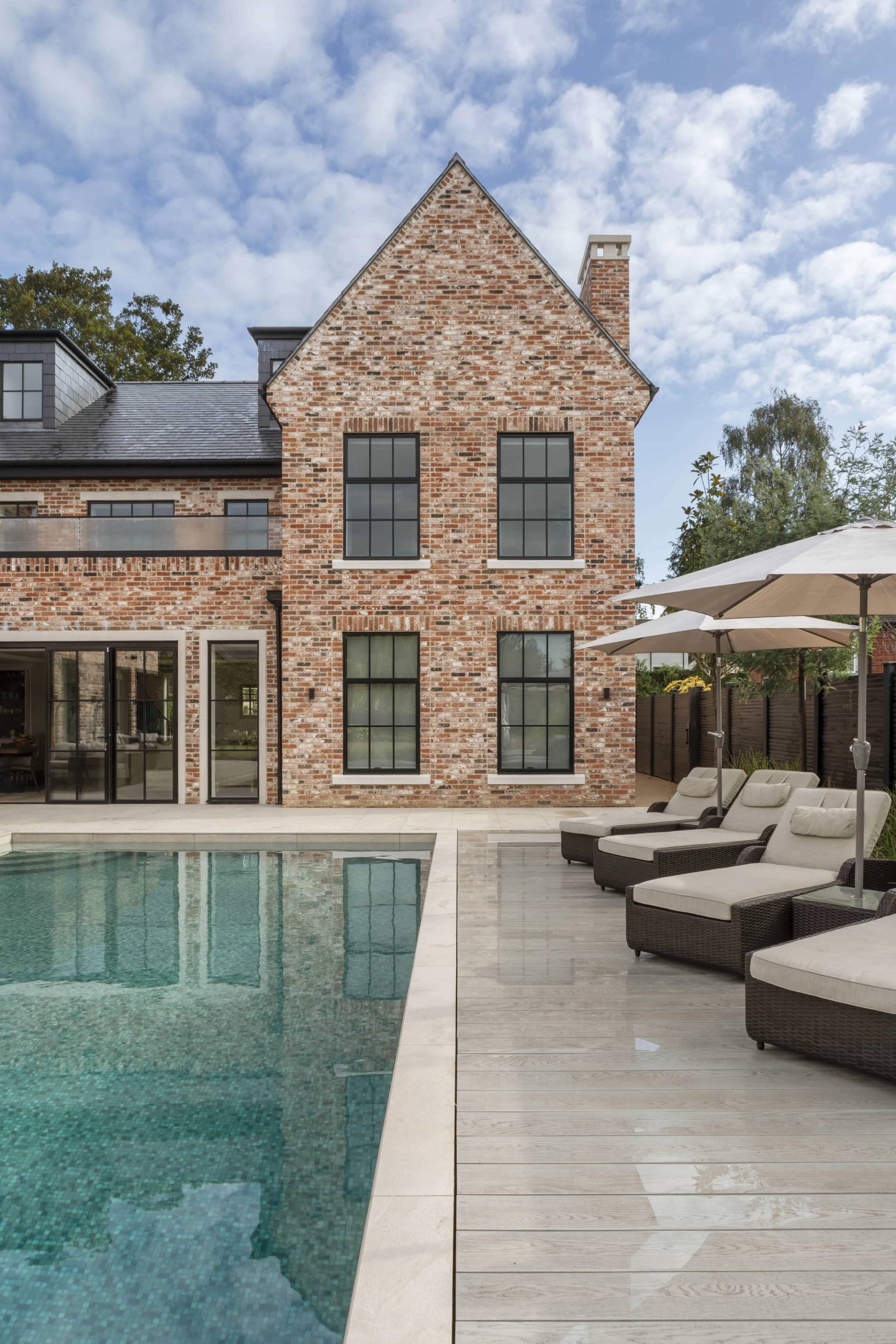 Luxury outdoor swimming pool shoot location in Buckinghamshire, HP18 featuring red brick mansion facade and sun loungers, Love Locations.