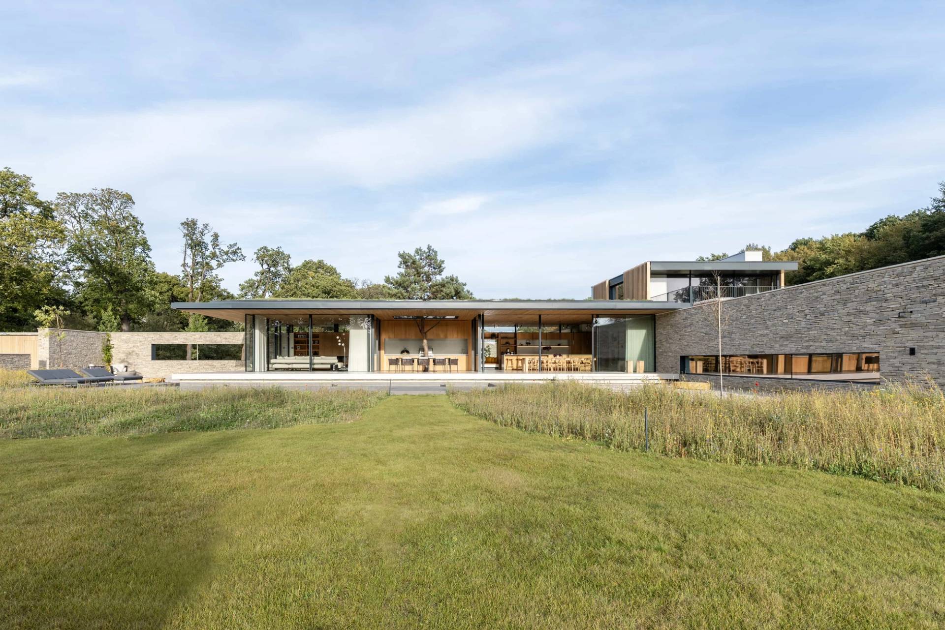 Expansive rear architectural elevation of a modern new build home set against open Essex countryside and wild grass meadows, Love Locations Fryerning.