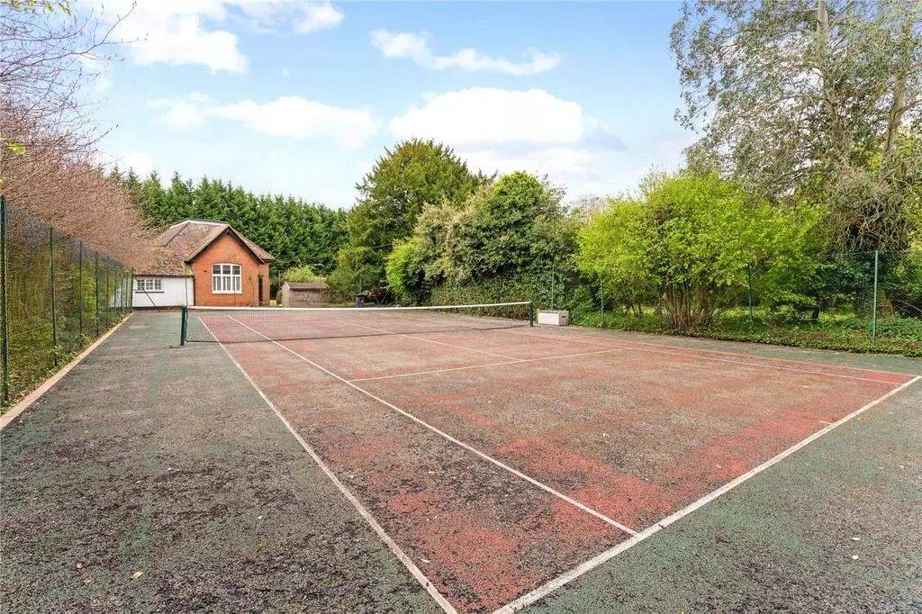 Private red-surface outdoor tennis court shoot space on country estate grounds in Berkshire from Love Locations.