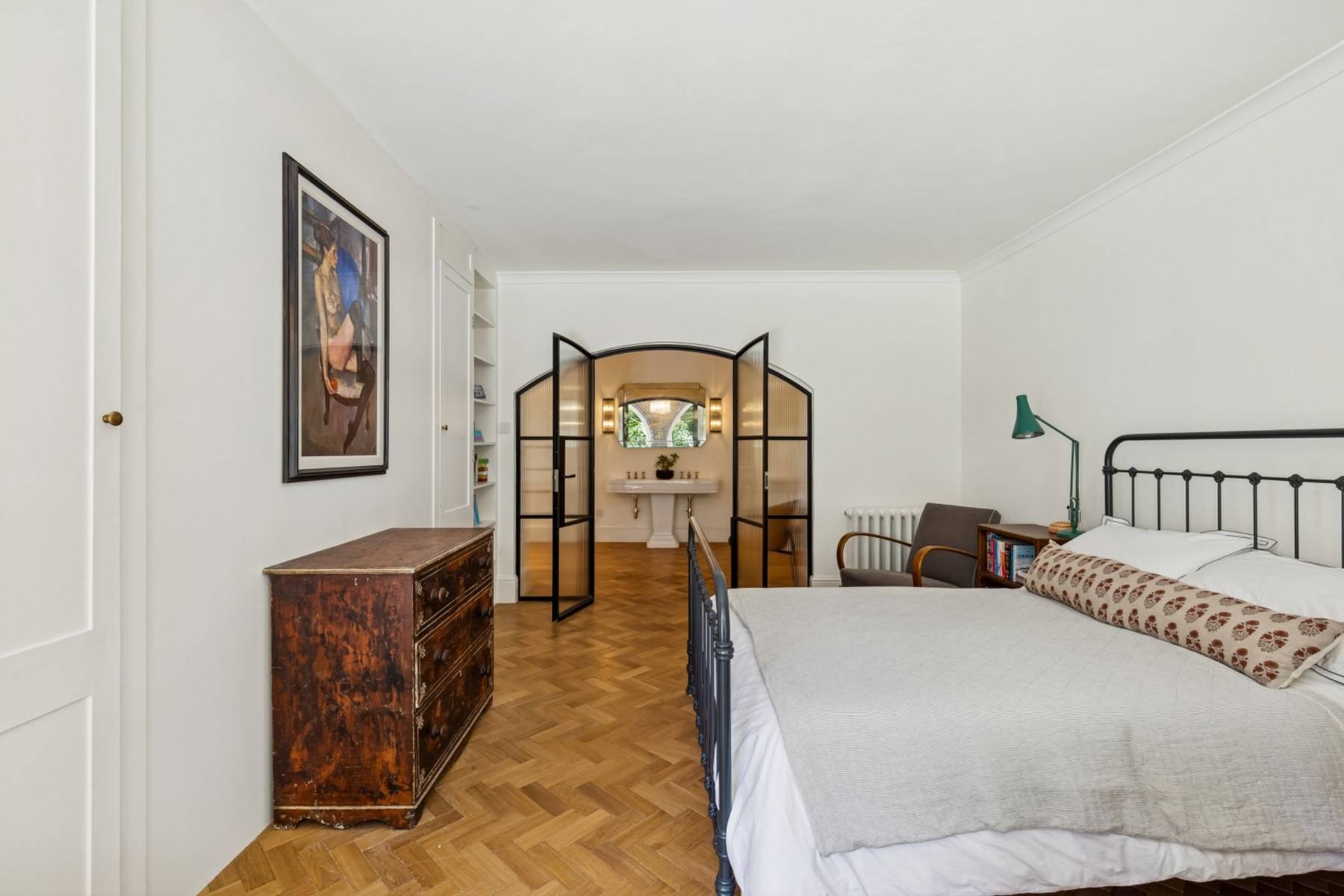 Stylish bedroom with dark wood dresser and glass panel doors in a Hampstead location house through Love Locations.