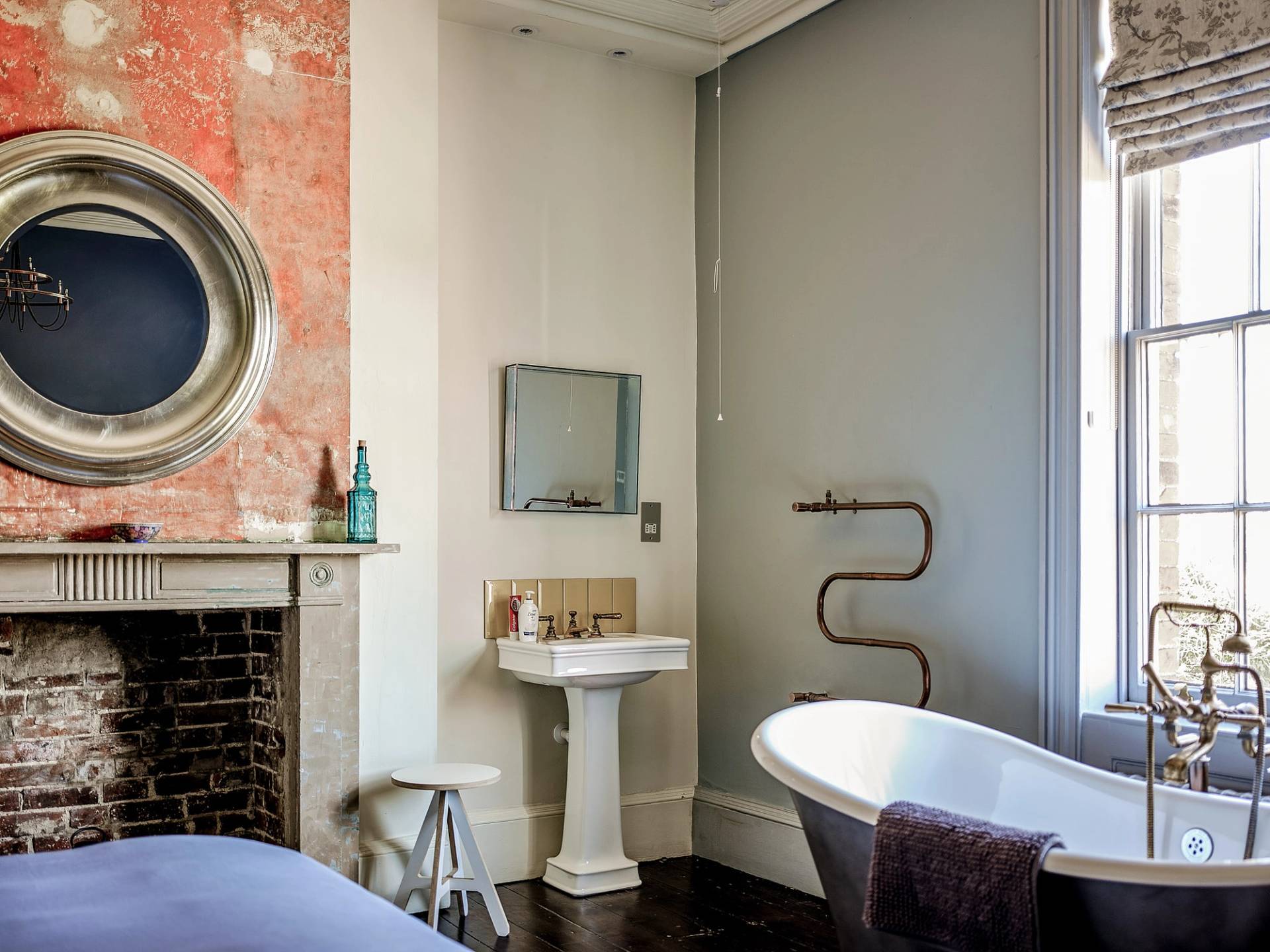 Spacious bathroom suite featuring a freestanding soaking tub, pedestal sink, and marble fireplace surround, perfect for spa product advertising, Love Locations ME13.