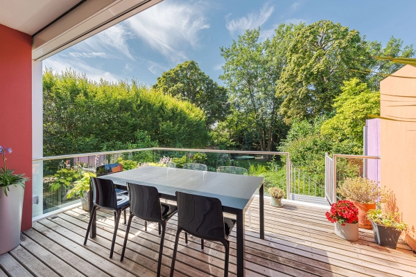 Elevated residential terrace deck surrounded by mature green trees and sleek glass railings, suitable for commercial filming backdrops, Love Locations W4.