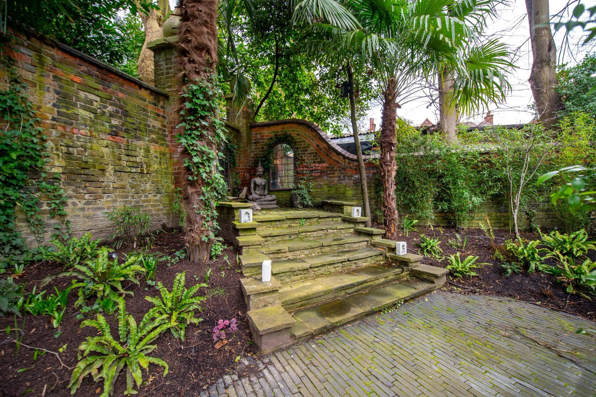 Historic stone garden steps winding up through lush green tropical plants, ivy-clad walls, and landscape lighting in Belsize Park, Love Locations NW3.