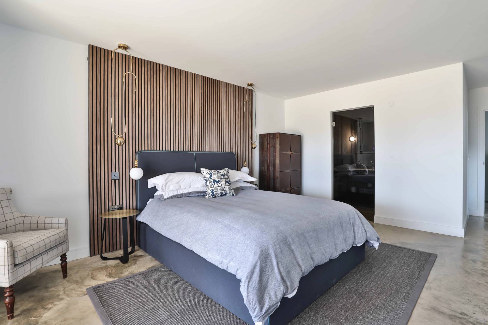 Master bedroom featuring a upholstered bed frame, slatted wood feature wall, and modern pendant lights, Love Locations CV23.