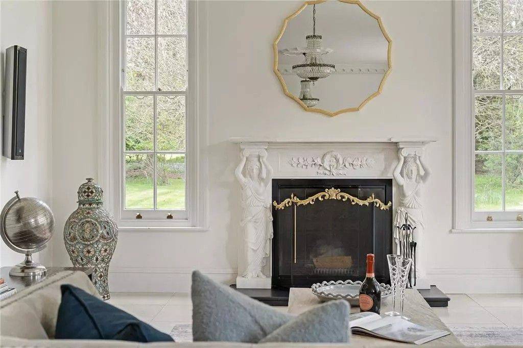 Detailed view of an ornate carved white marble fireplace surround with gold mirror accents in an Georgian country house by Love Locations.