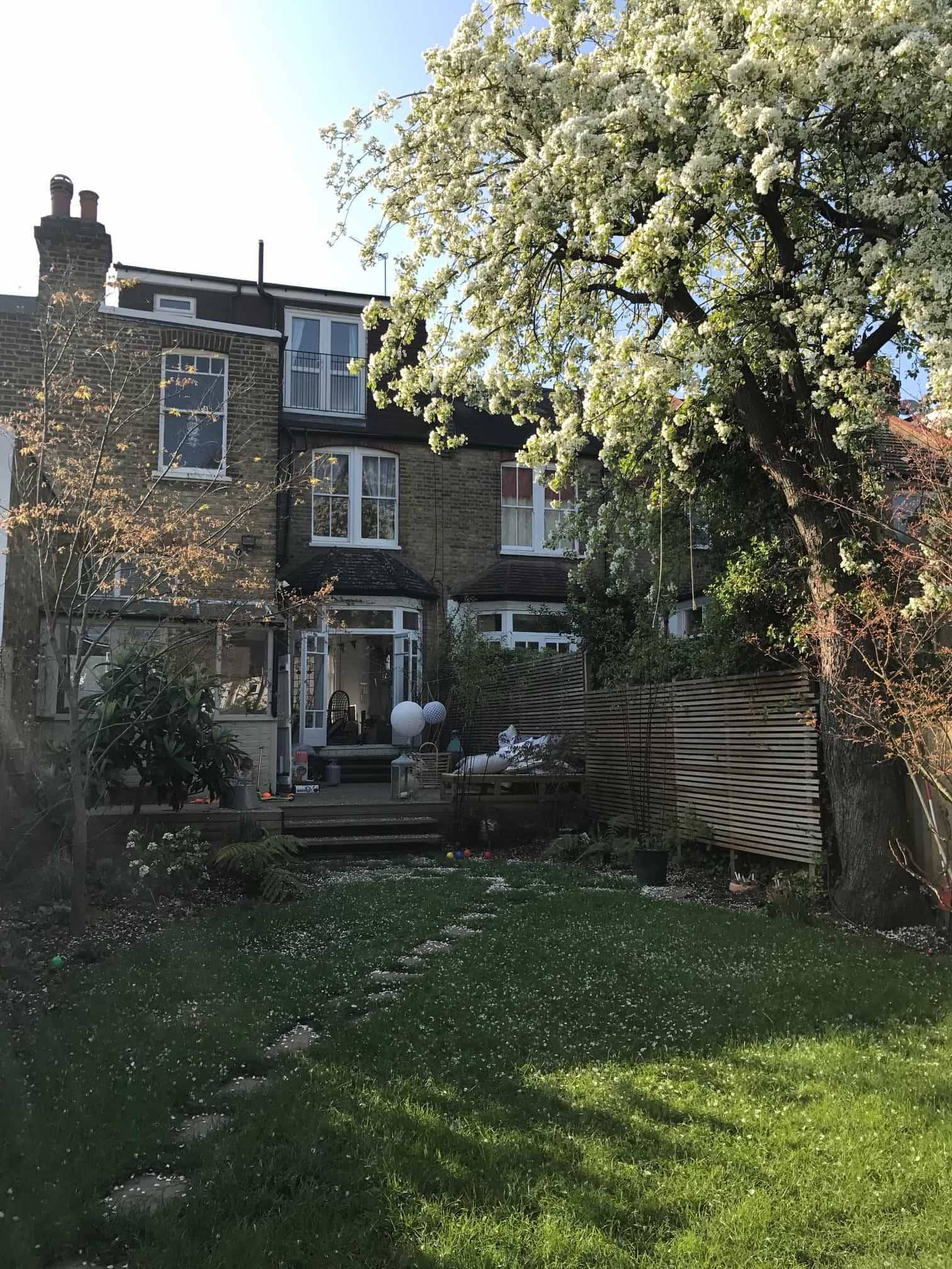 Rear exterior view of a Victorian period property showing a loft extension dormer and green garden grounds, Love Locations N13.