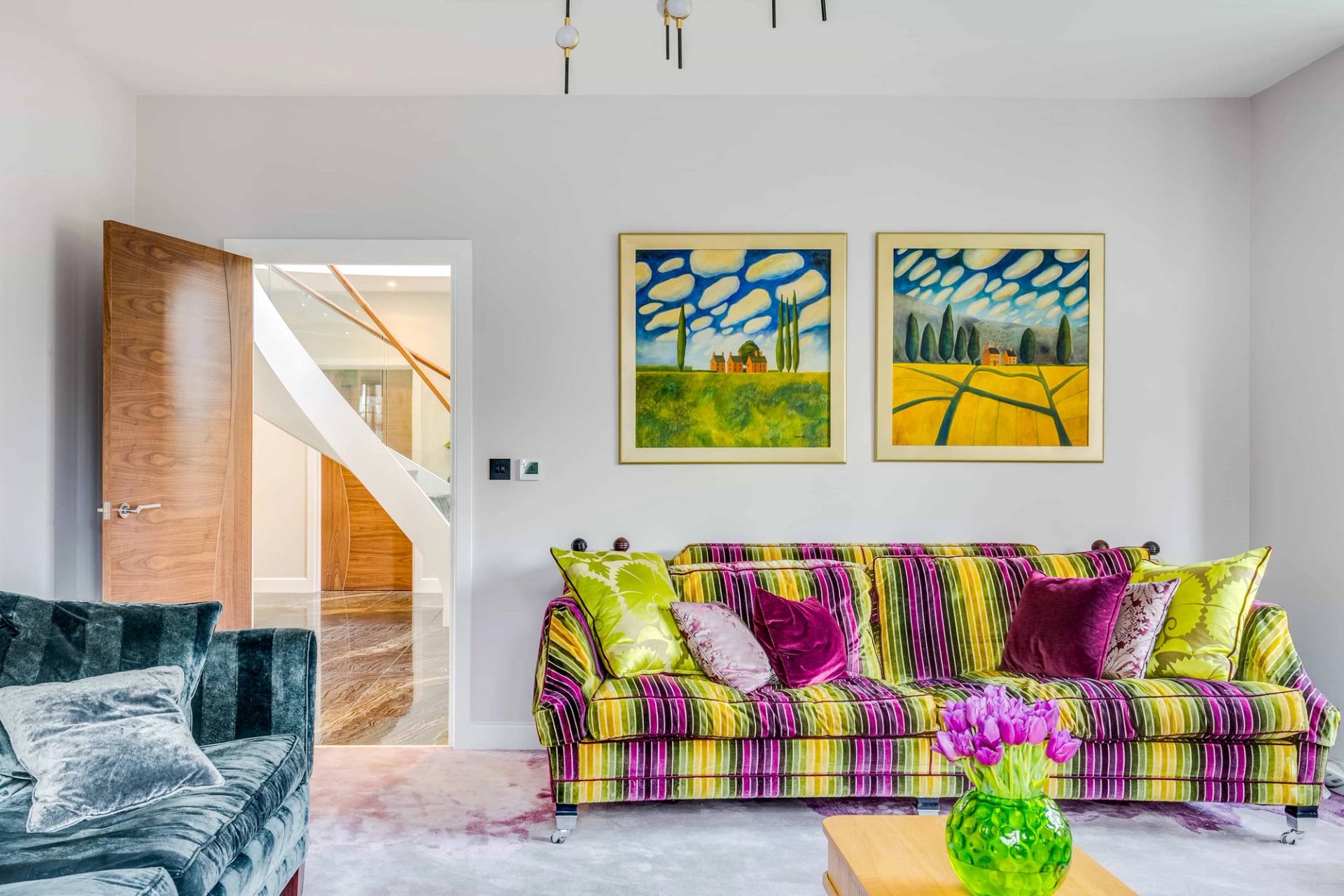 Striped sofa set under colorful framed abstract art prints in a light-filled living room, Love Locations CB2.