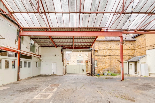 Covered industrial courtyard location space with rustic brick walls and glass roof panels, curated by Love Locations Richmond.