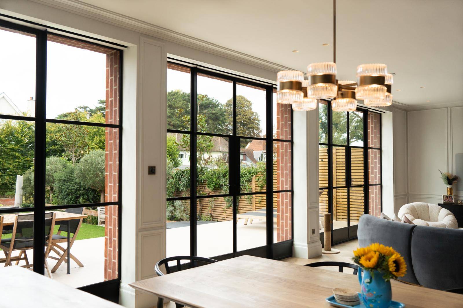 Black steel Crittall patio doors opening onto an outdoor dining terrace in Teddington, Love Locations TW11.